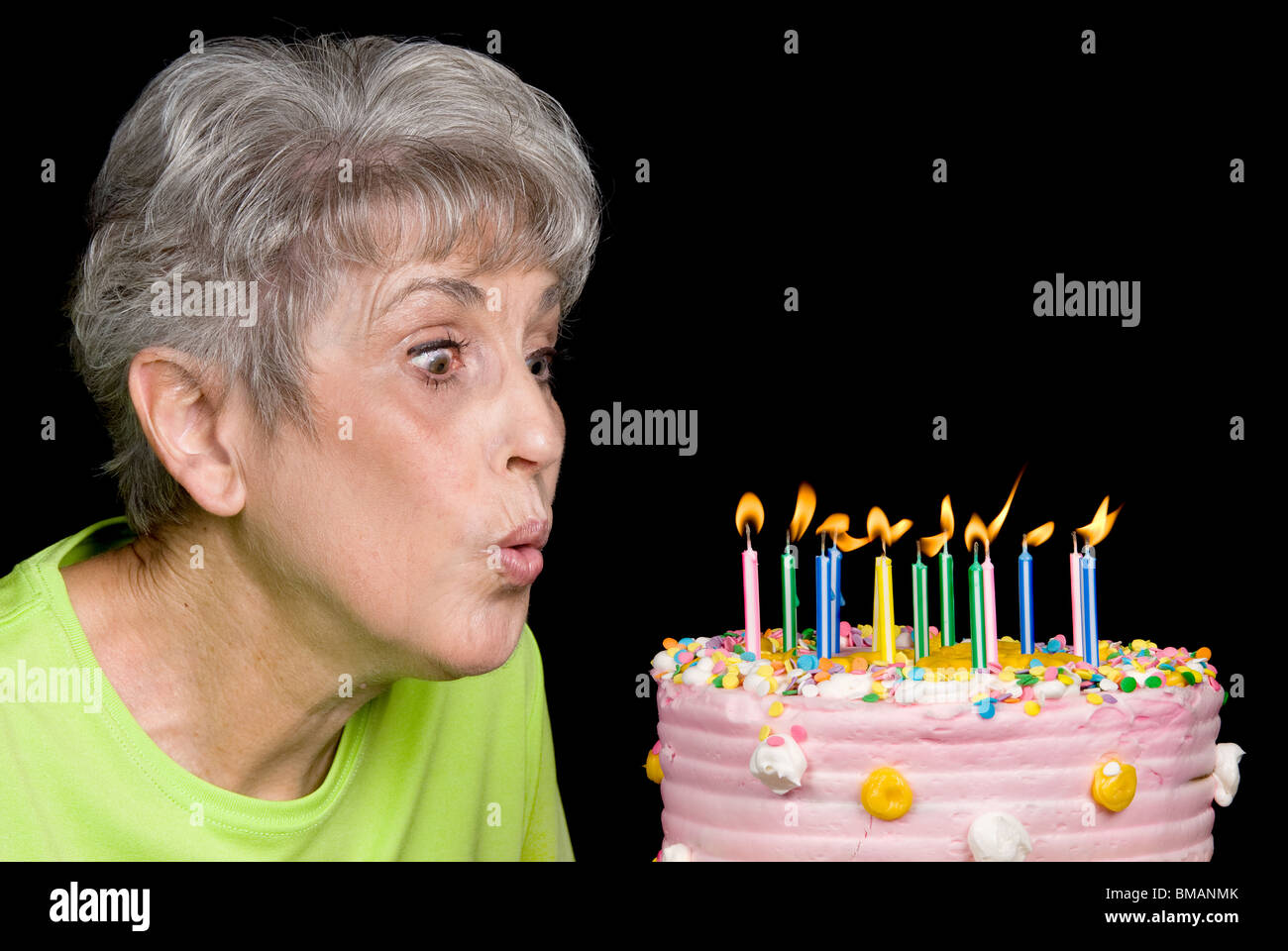 Una femmina senior si brucia candele su una torta. Ideale per il compleanno, anniversario o qualsiasi altra celebrazione inferenza. Foto Stock