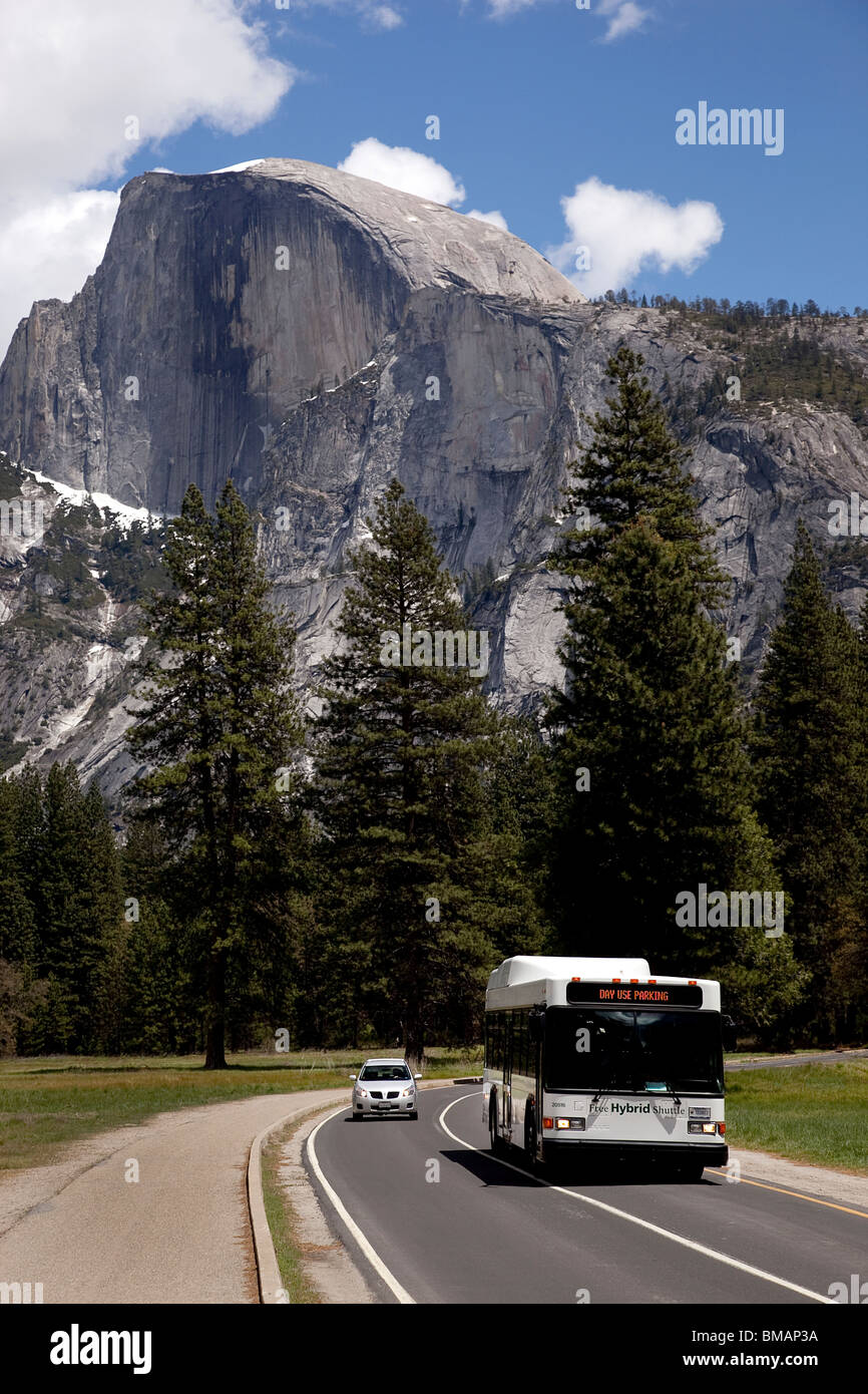 Il parco nazionale di Yosemite Park bus navetta su National Park road con mezza cupola picco in background. California USA Foto Stock