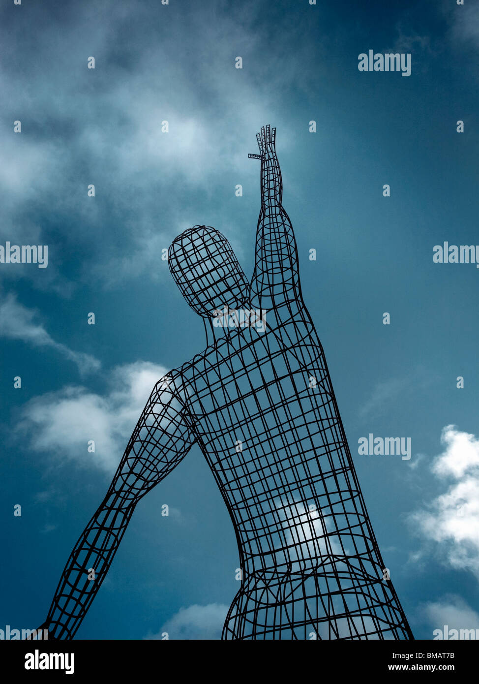 La scultura di un uomo lo stiramento fino a raggiungere il cielo blu con moody sky, Foto Stock