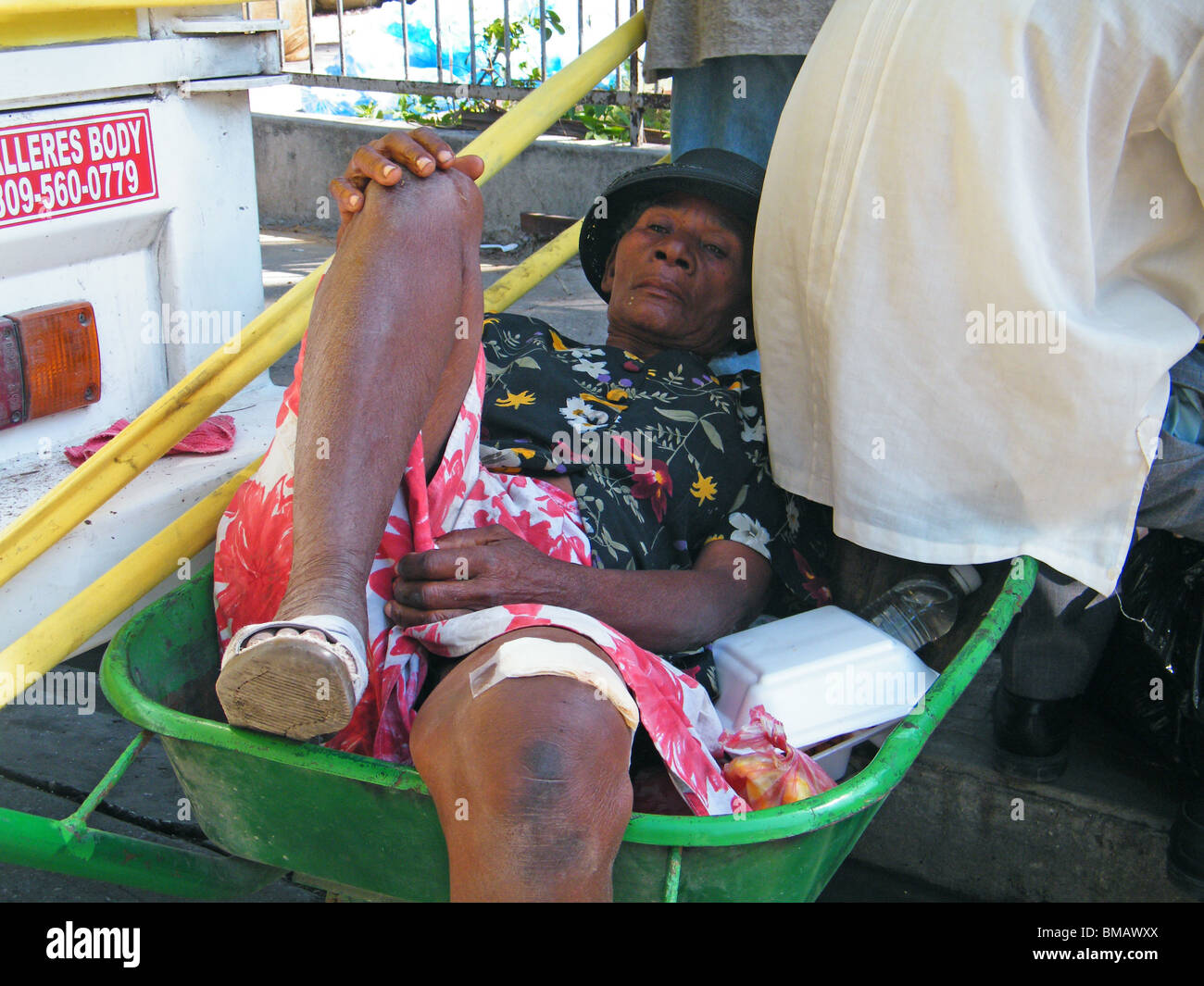 Un ferito sopravvissuto al terremoto di Haiti si trova in una carriola come ella attende per un trattamento medico Foto Stock