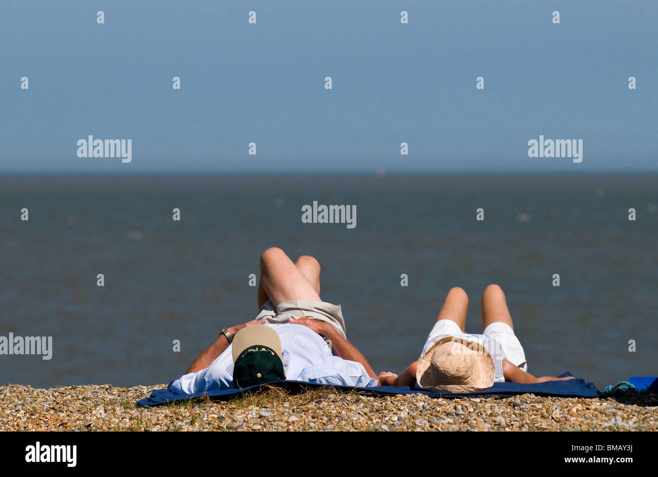 Due persone a prendere il sole sulla spiaggia di Sizewell nel Suffolk. Foto di Gordon Scammell Foto Stock