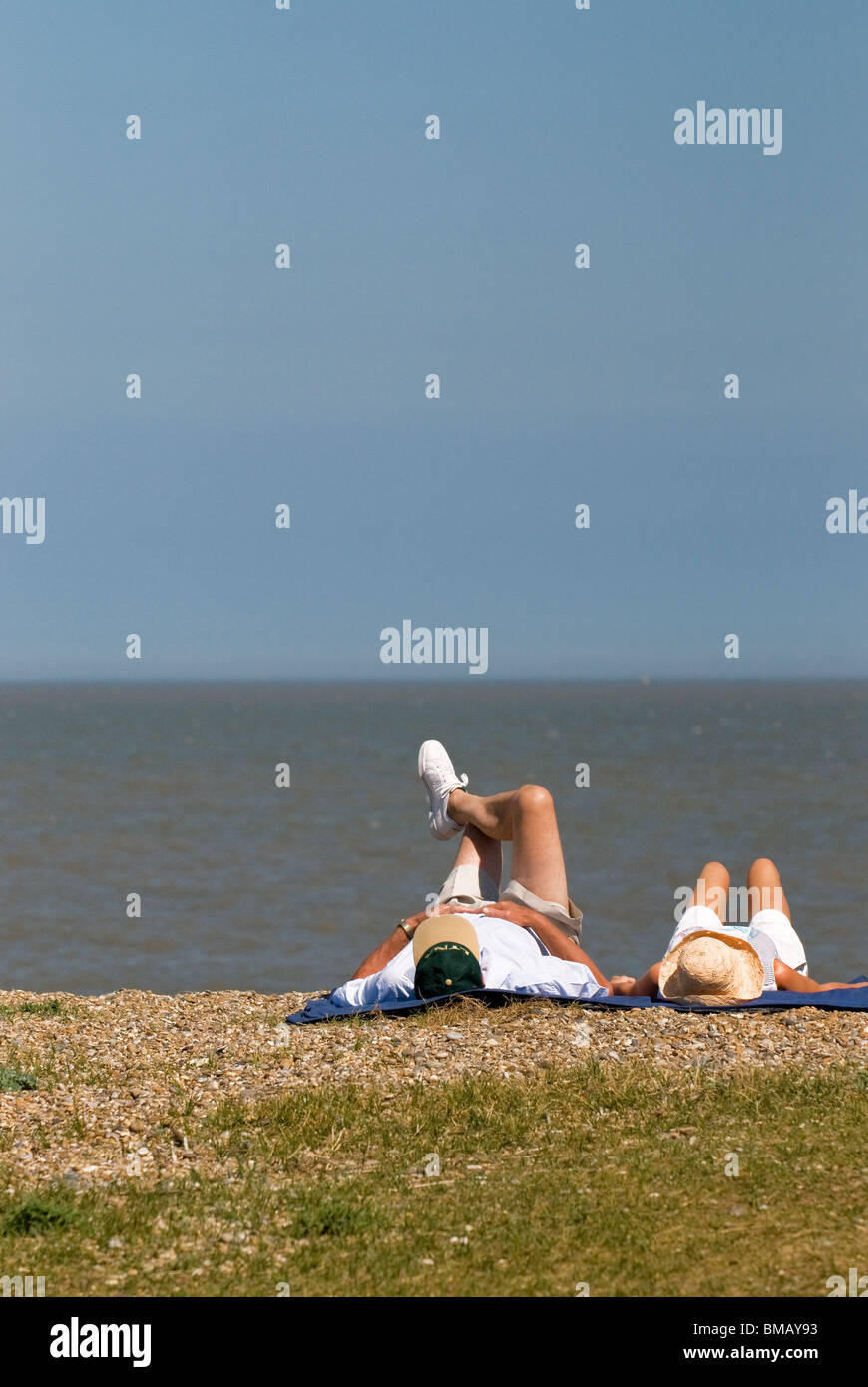 Due persone a prendere il sole sulla spiaggia di Sizewell nel Suffolk. Foto di Gordon Scammell Foto Stock