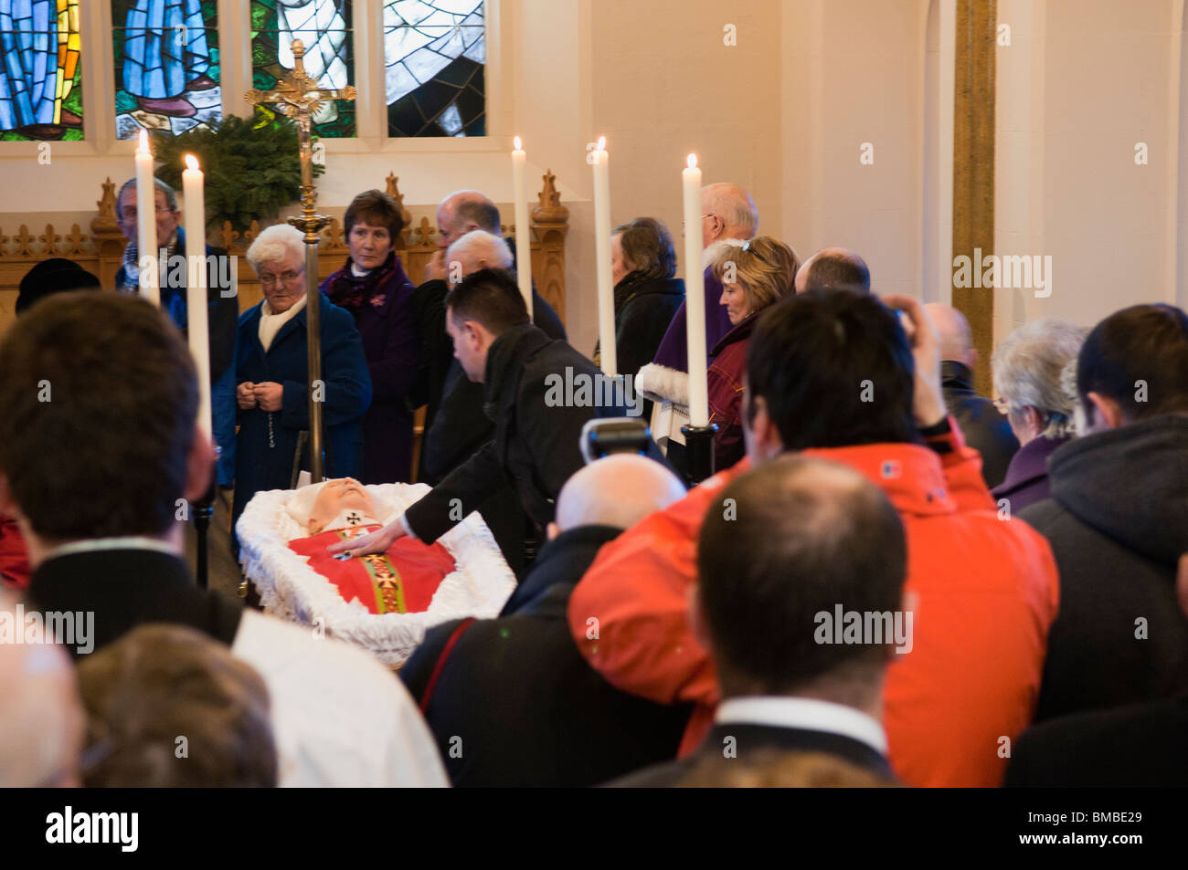Mourner tocca il Cardinale Cahal Daly come egli risiede nello Stato presso il St Peters Cathedral, Belfast Foto Stock