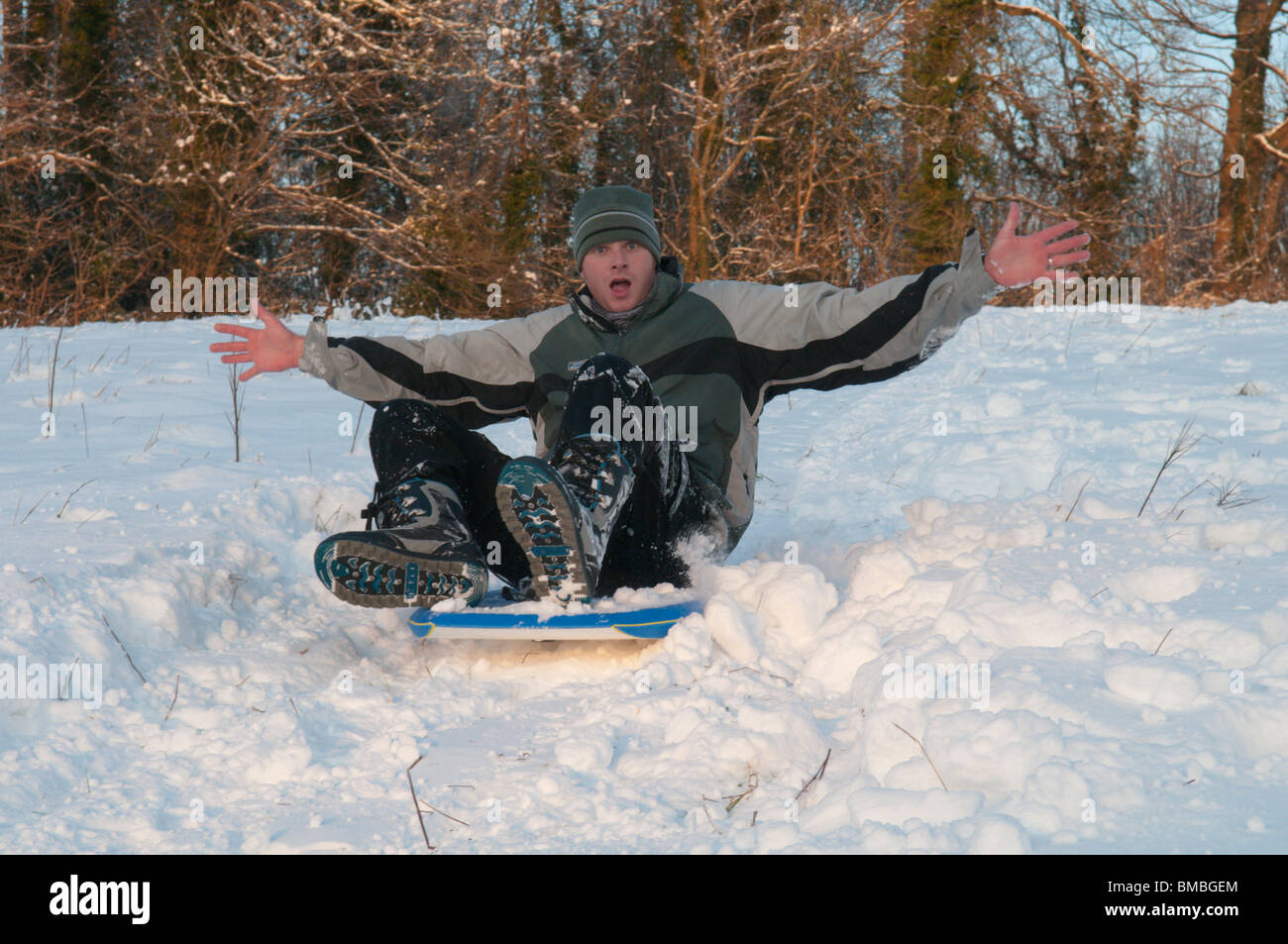 Uomo sulla slitta messing about in neve. Sussex, Regno Unito. Foto Stock