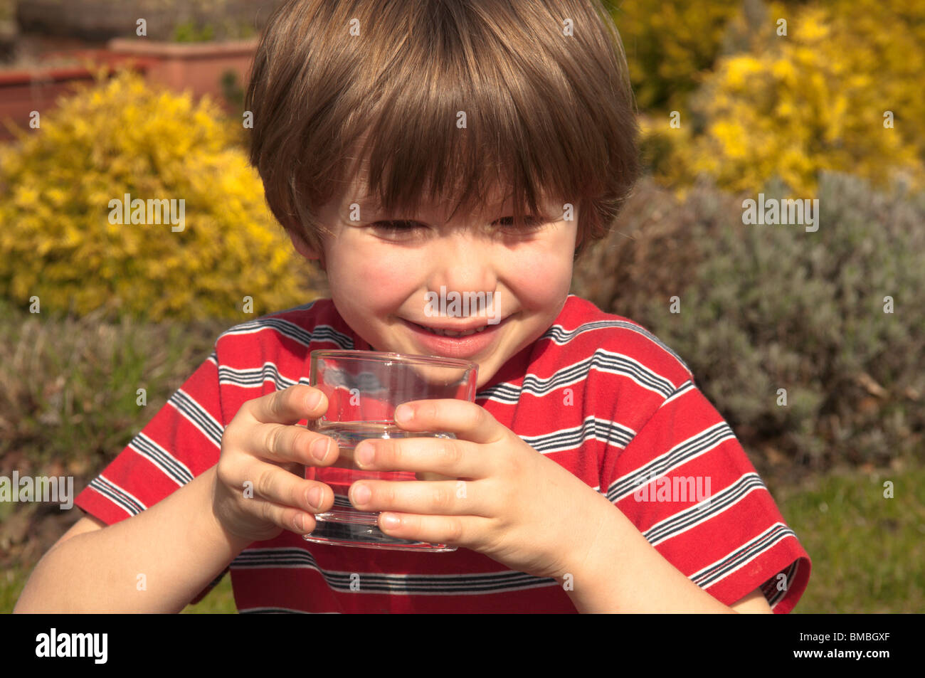 Quattro anni di old boy sensazione calda e acqua potabile da un vetro a raffreddare. Foto Stock