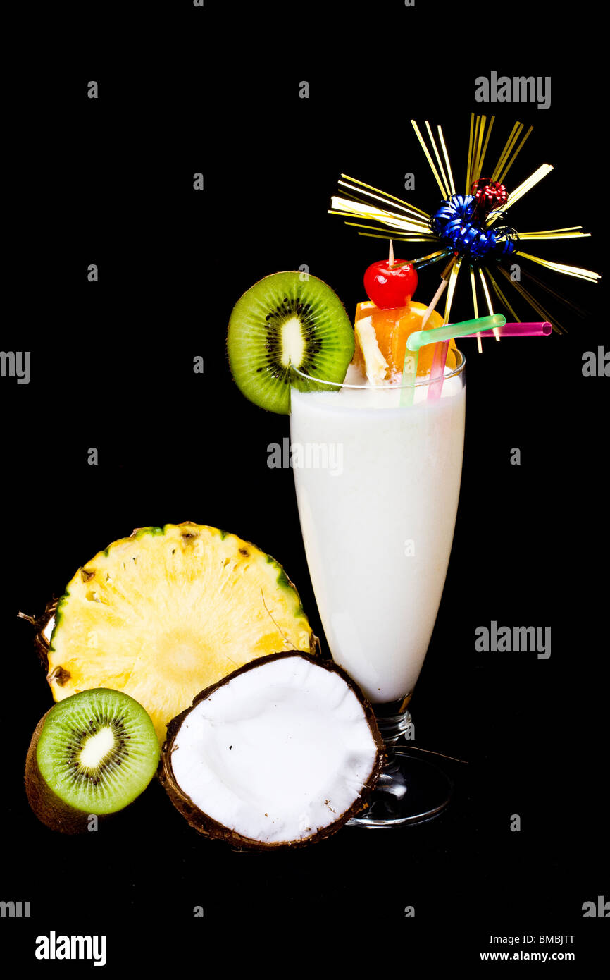 La Pina Colada su sfondo nero, guarnite con fette di ananas, kiwi e cocco. Foto Stock