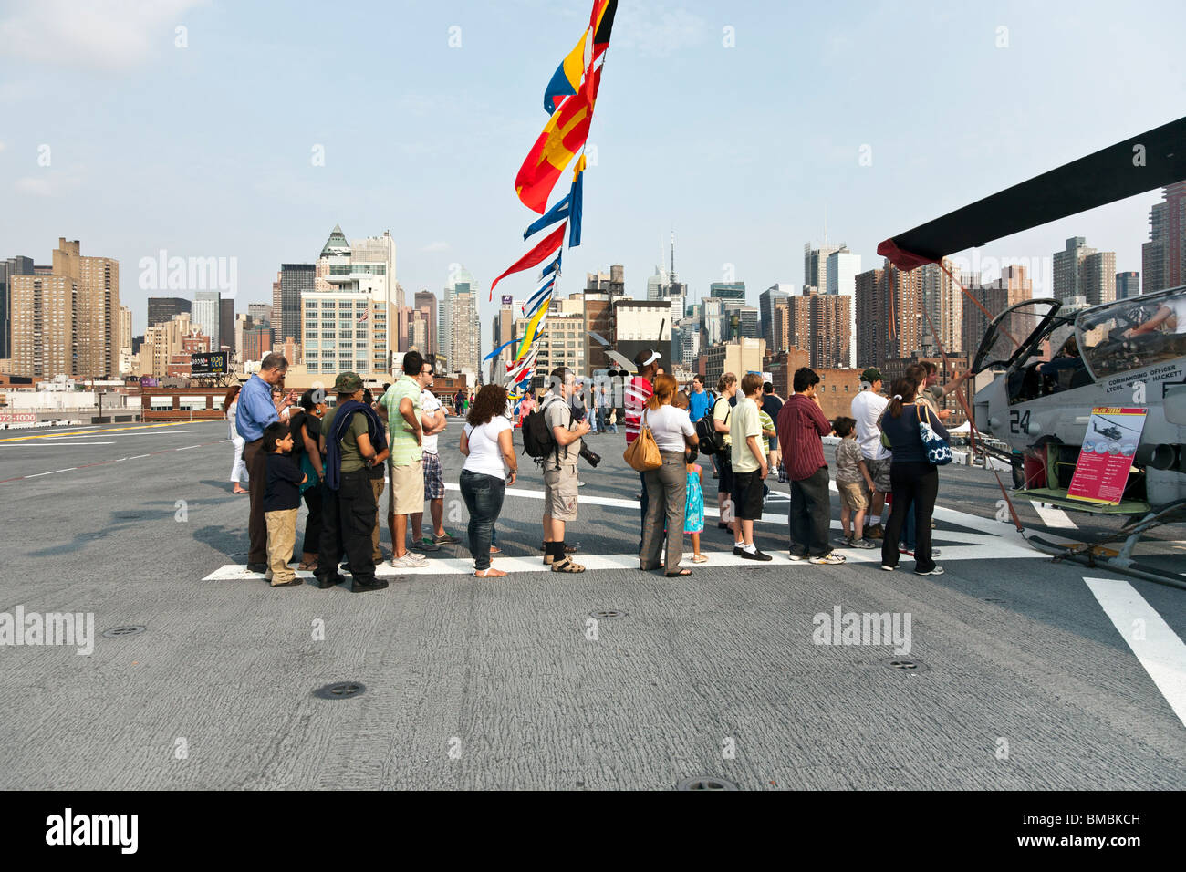 Diversi gruppi di persone in coda per entrare in cabina di pilotaggio di elicottero Cobra sul ponte di volo della USS Iwo Jima durante la settimana della flotta NYC Foto Stock