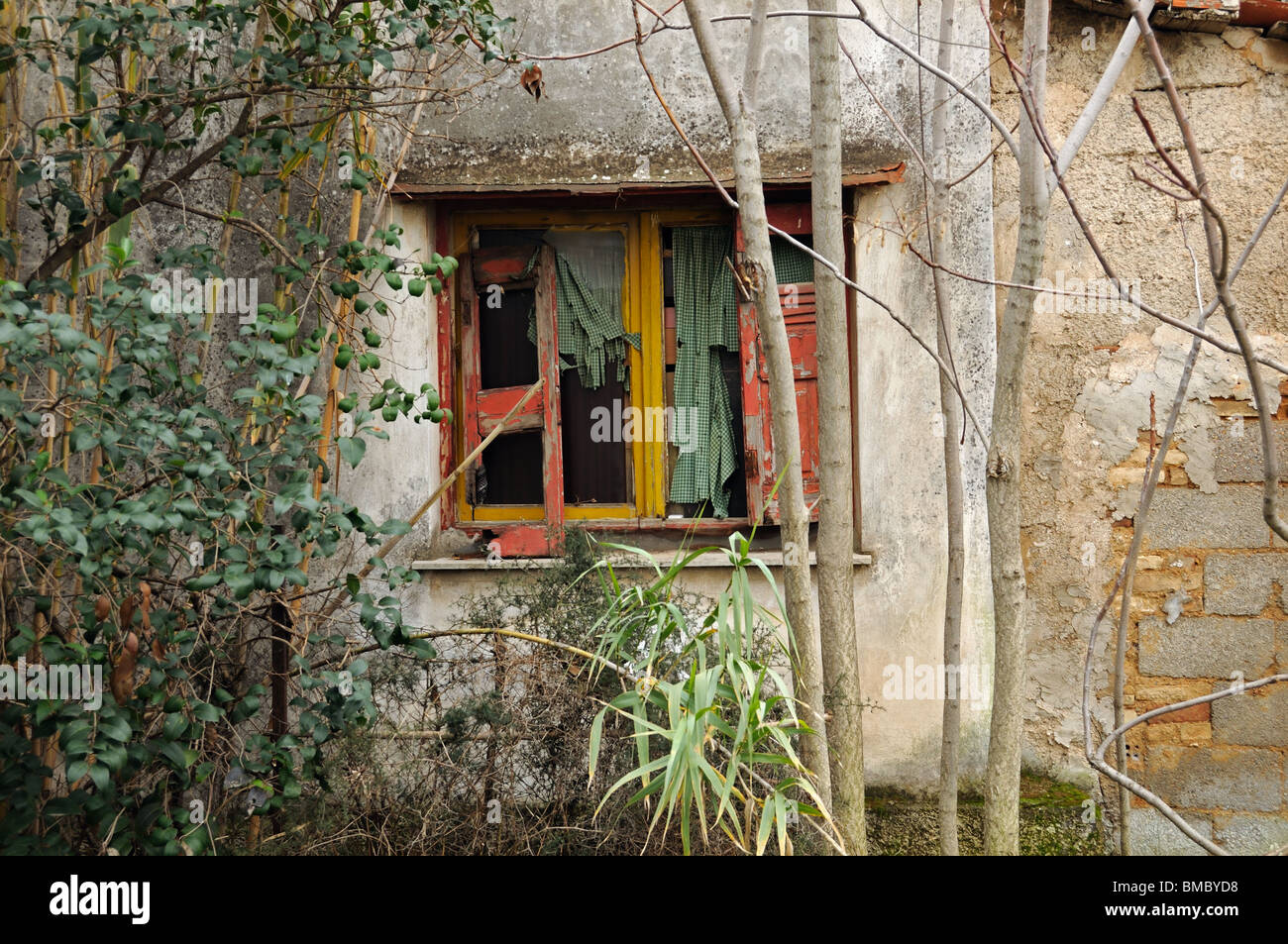 Vetro rotto dello shutter e ragged oscuranti. Weathered casa abbandonata parete. Foto Stock