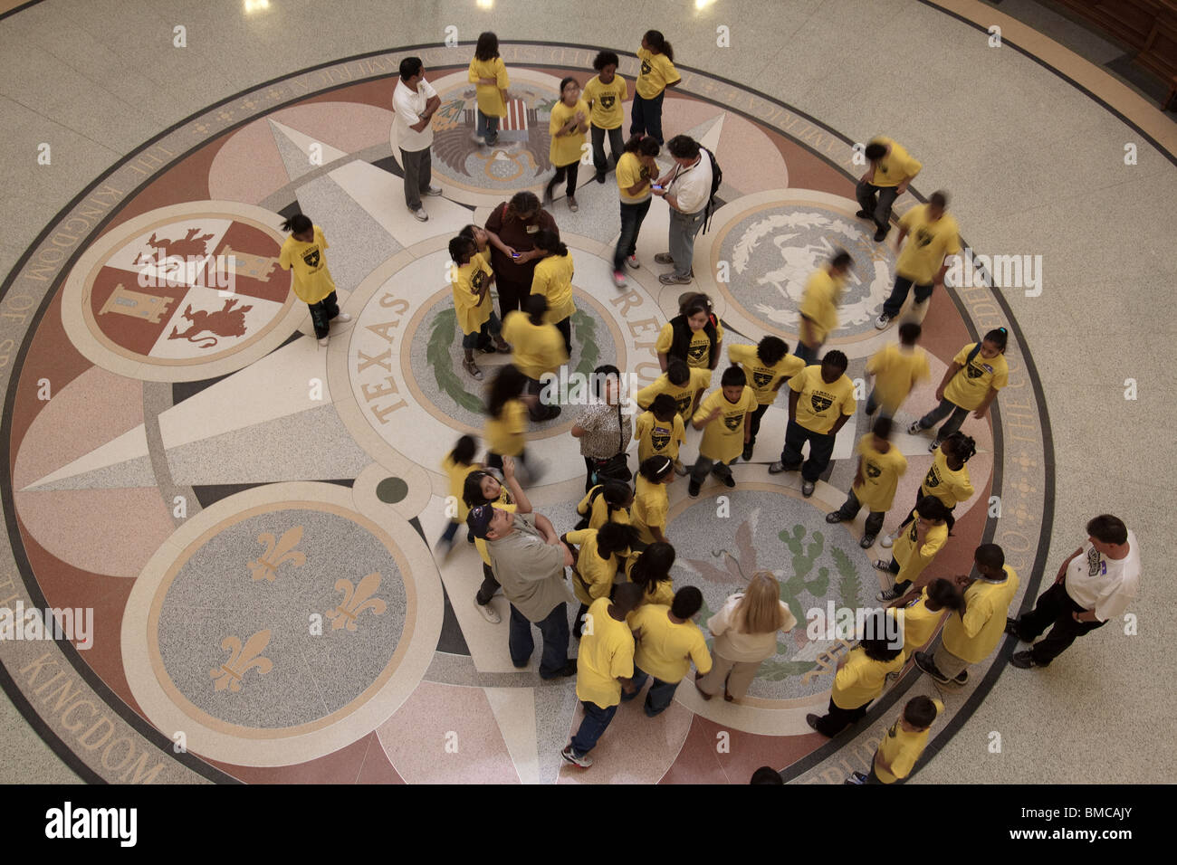 La scuola dei bambini guardando le guarnizioni sul pavimento del Texas State Capitol Building rotunda di Austin Foto Stock