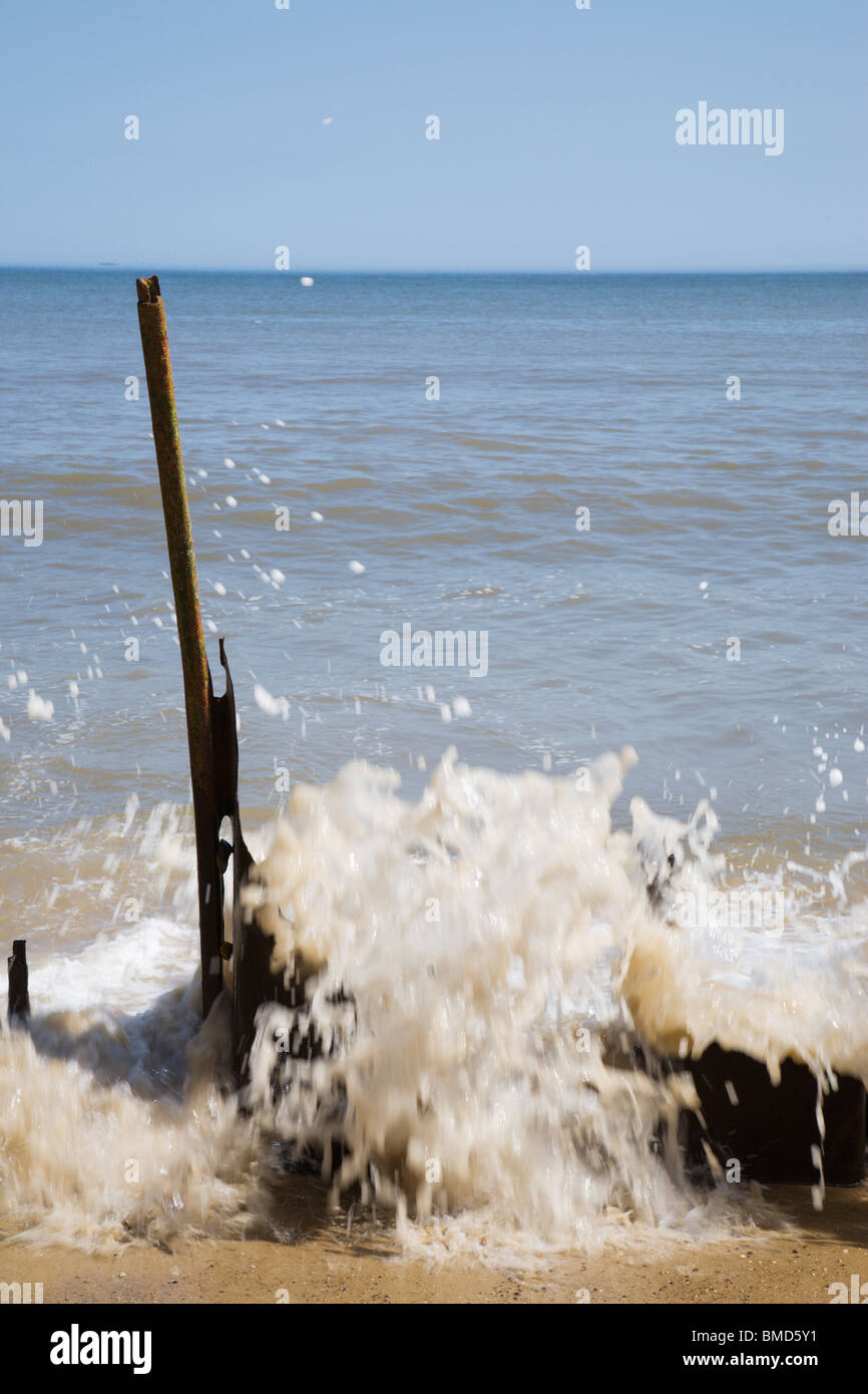 Il mare che si infrangono sulle rusty resti delle difese del mare. Foto Stock