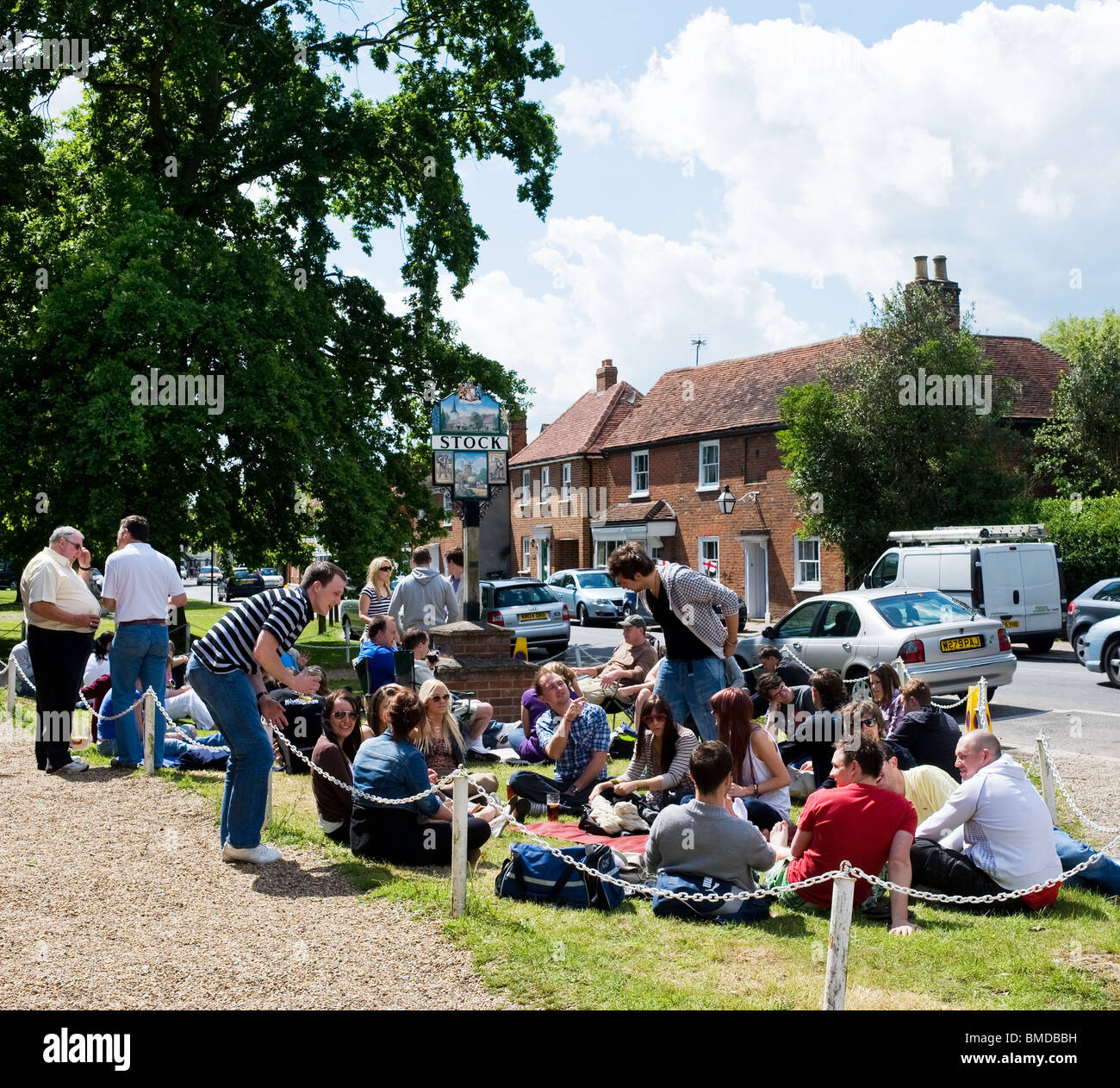 Persone sedute sull'erba nel villaggio di Stock in Essex. Foto di Gordon Scammell Foto Stock