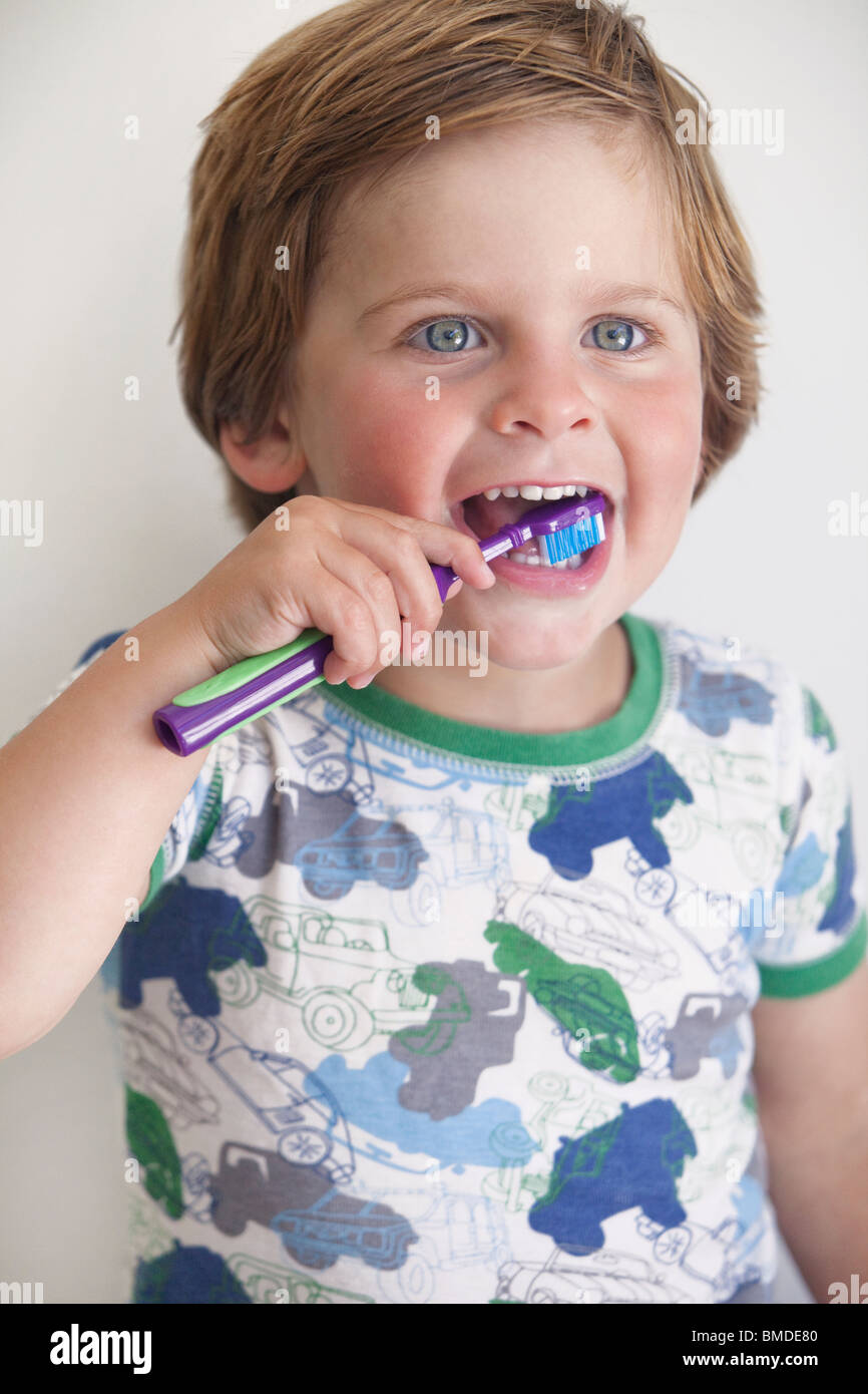 Ragazzo giovane spazzolando i suoi denti Foto Stock