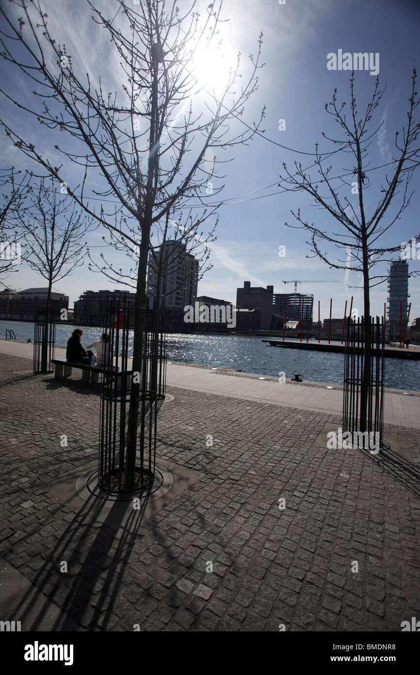 Dublin Docklands nel sole brillante con due persone sedute su un banco di lavoro Foto Stock