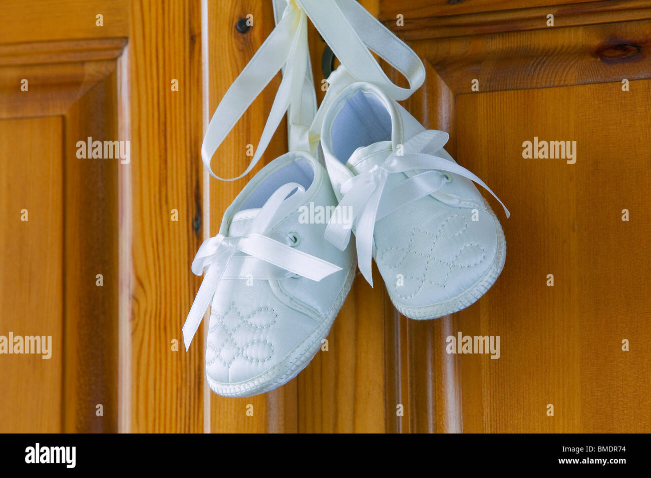 Battesimo di scarpe o stivali per un bambino legato insieme con nastro di  seta, appeso ad una anta di armadio Foto stock - Alamy