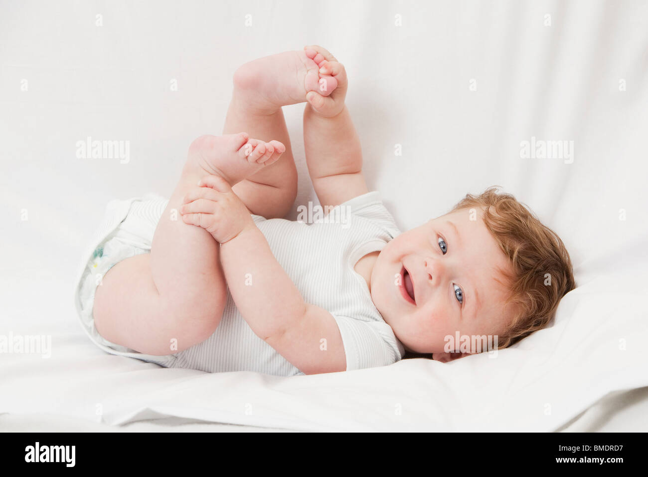 Un bambino di 6 mesi boy recante sulla sua schiena su uno sfondo bianco foglio Foto Stock