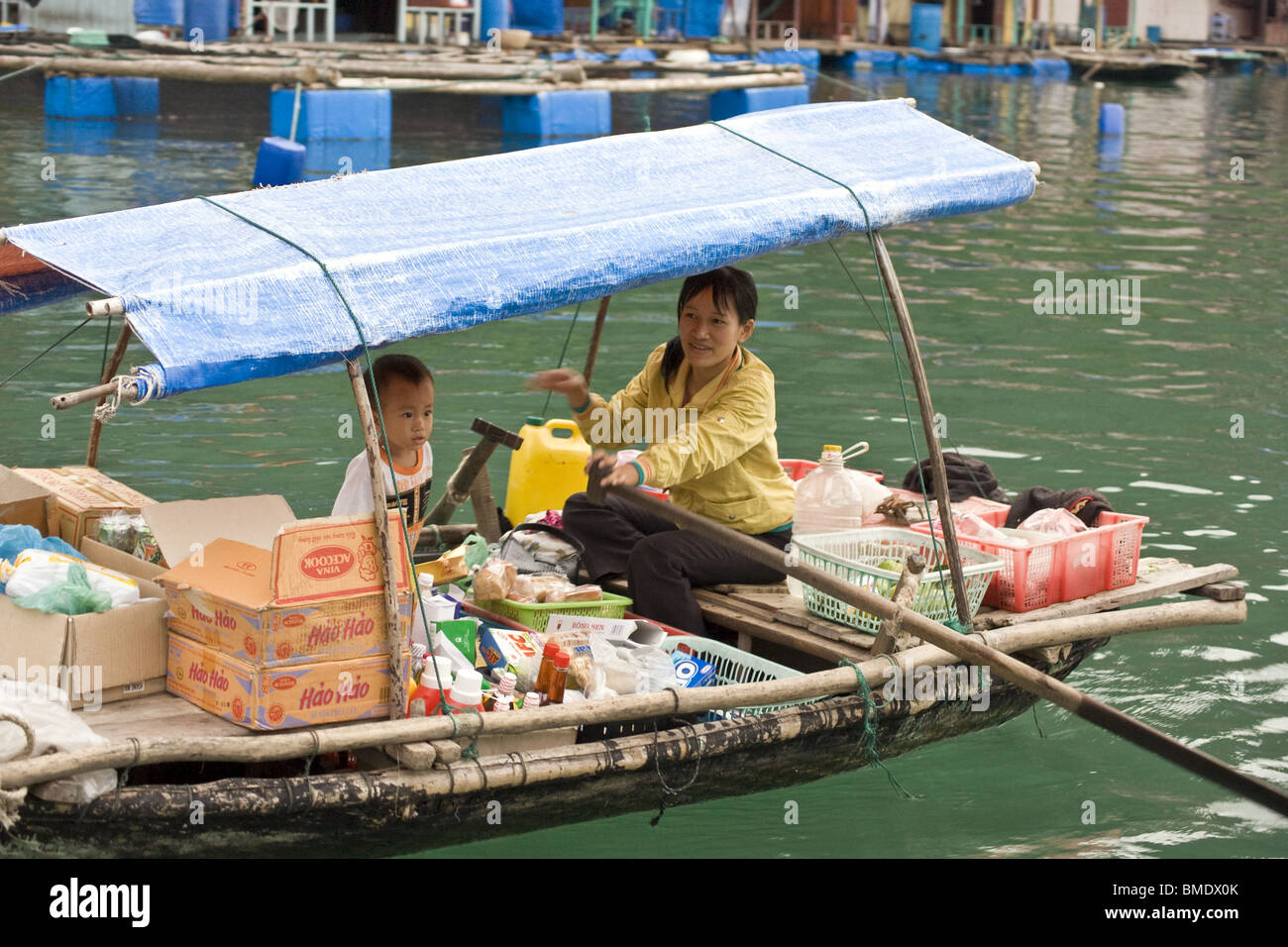 La madre e il bambino di vendita di alimenti e bevande da barca a remi in Halong Bay, Vietnam Foto Stock