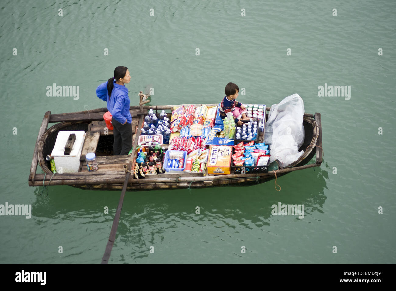 La madre e il bambino di vendita di alimenti e bevande da barca a remi in Halong Bay, Vietnam Foto Stock
