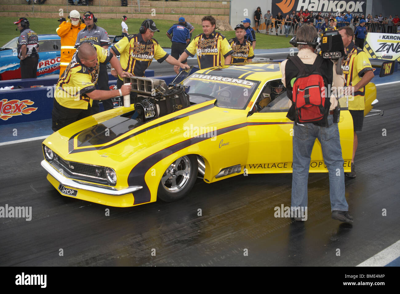 Australian Top Doorslammer drag racer, Stuart Vescovo, siede sulla linea di partenza mentre il suo pit crew preparare la sua sovralimentato Camaro Foto Stock