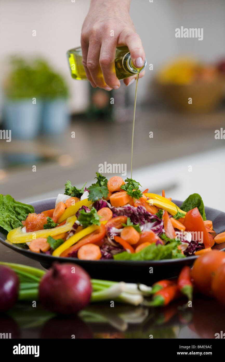 Donna versando olio su verdure, Svezia. Foto Stock Donna versando olio su verdure, Svezia. Foto Stock