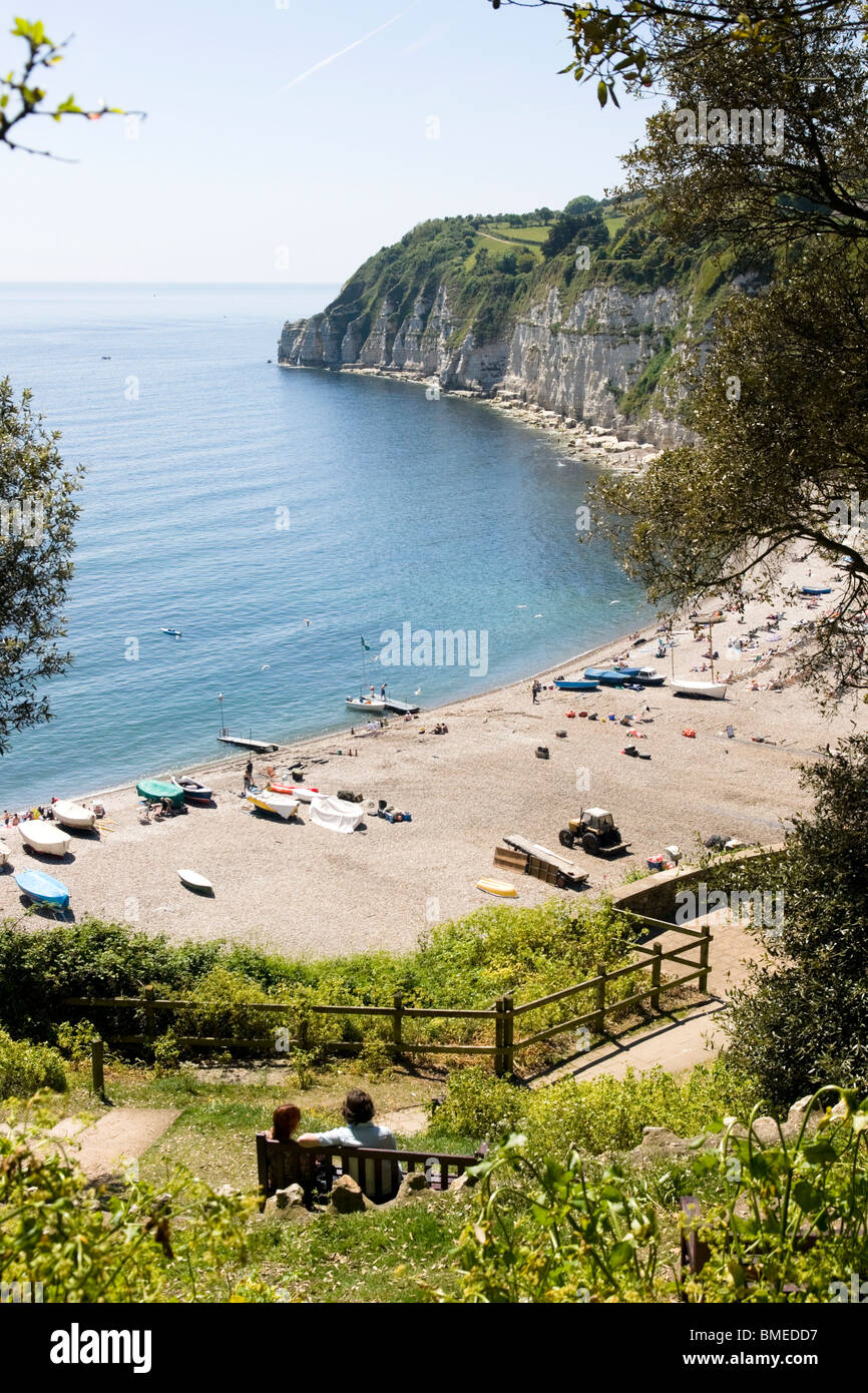 La coppia si sedeva su una panchina che si affacciava sulla spiaggia di Pebbly, Devon, Inghilterra, Regno Unito Foto Stock