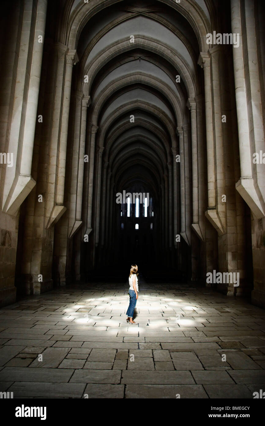 Donna visitando la grande maestosa chiesa, con una luce magica su di lei Foto Stock