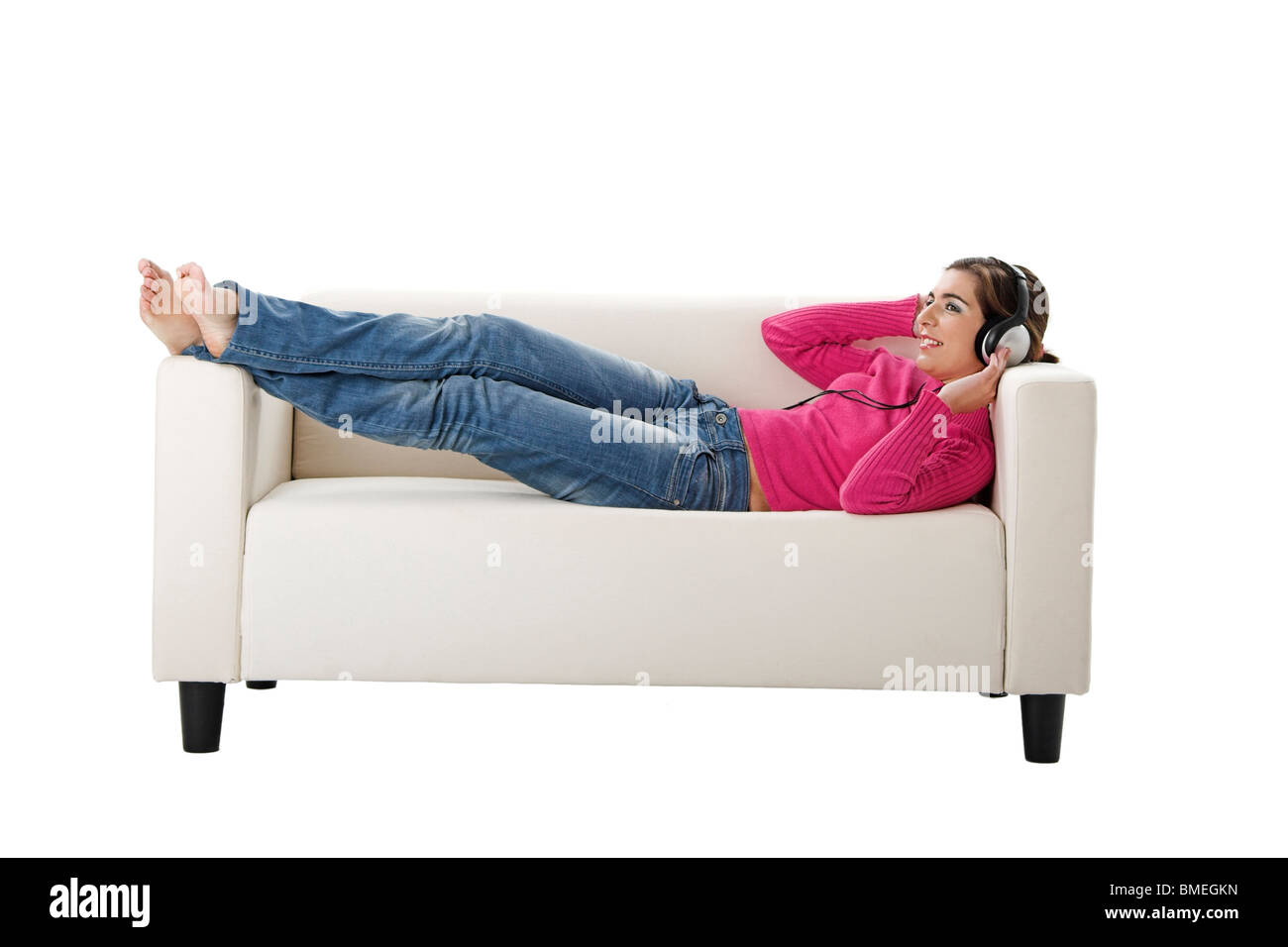 Bella donna sdraiata sul divano e ascoltare musica con le cuffie Foto Stock