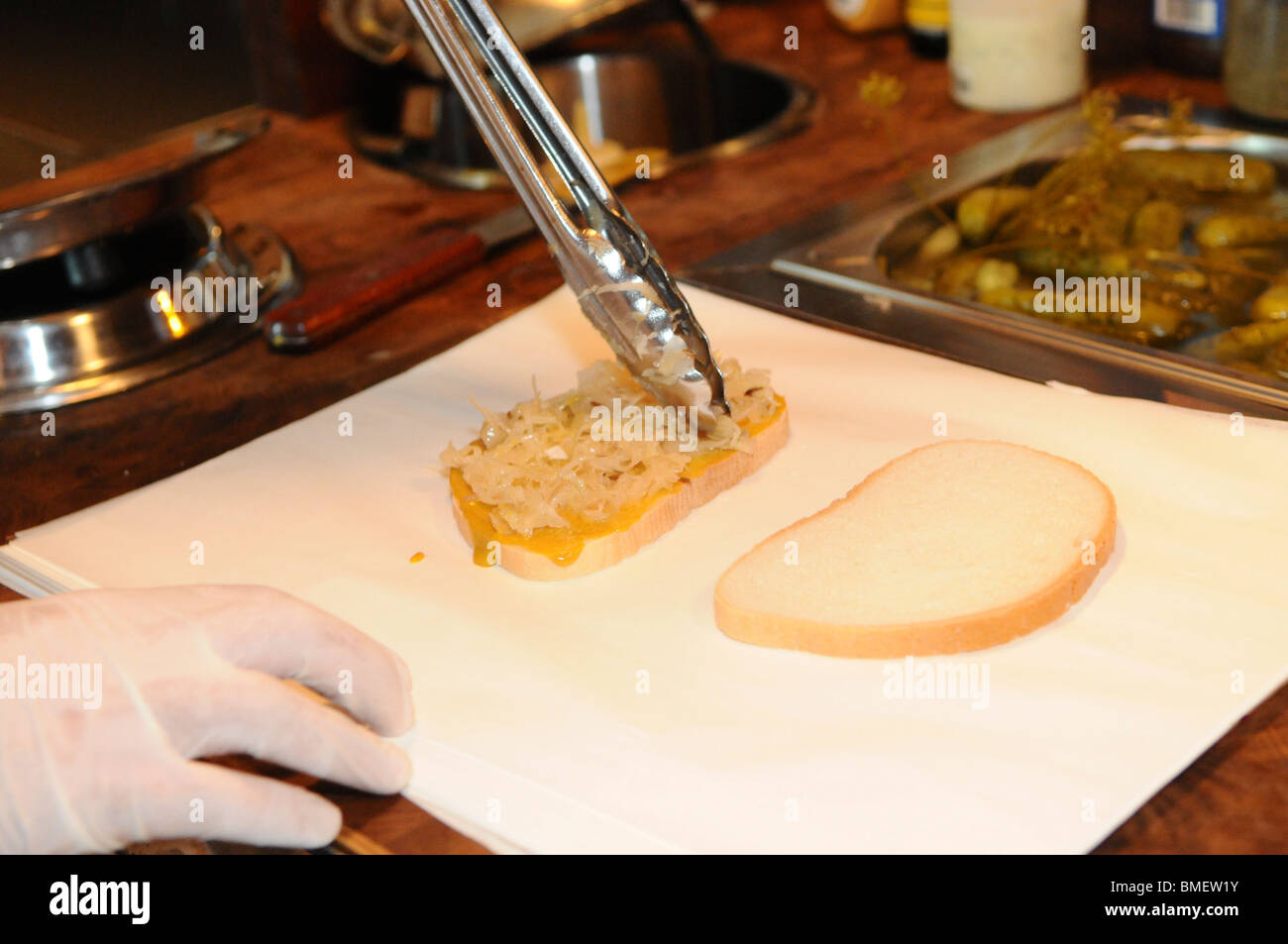 La preparazione di un cibo Kosher New York Deli stile di " corned beef " panino aggiungendo uno strato di crauti Foto Stock
