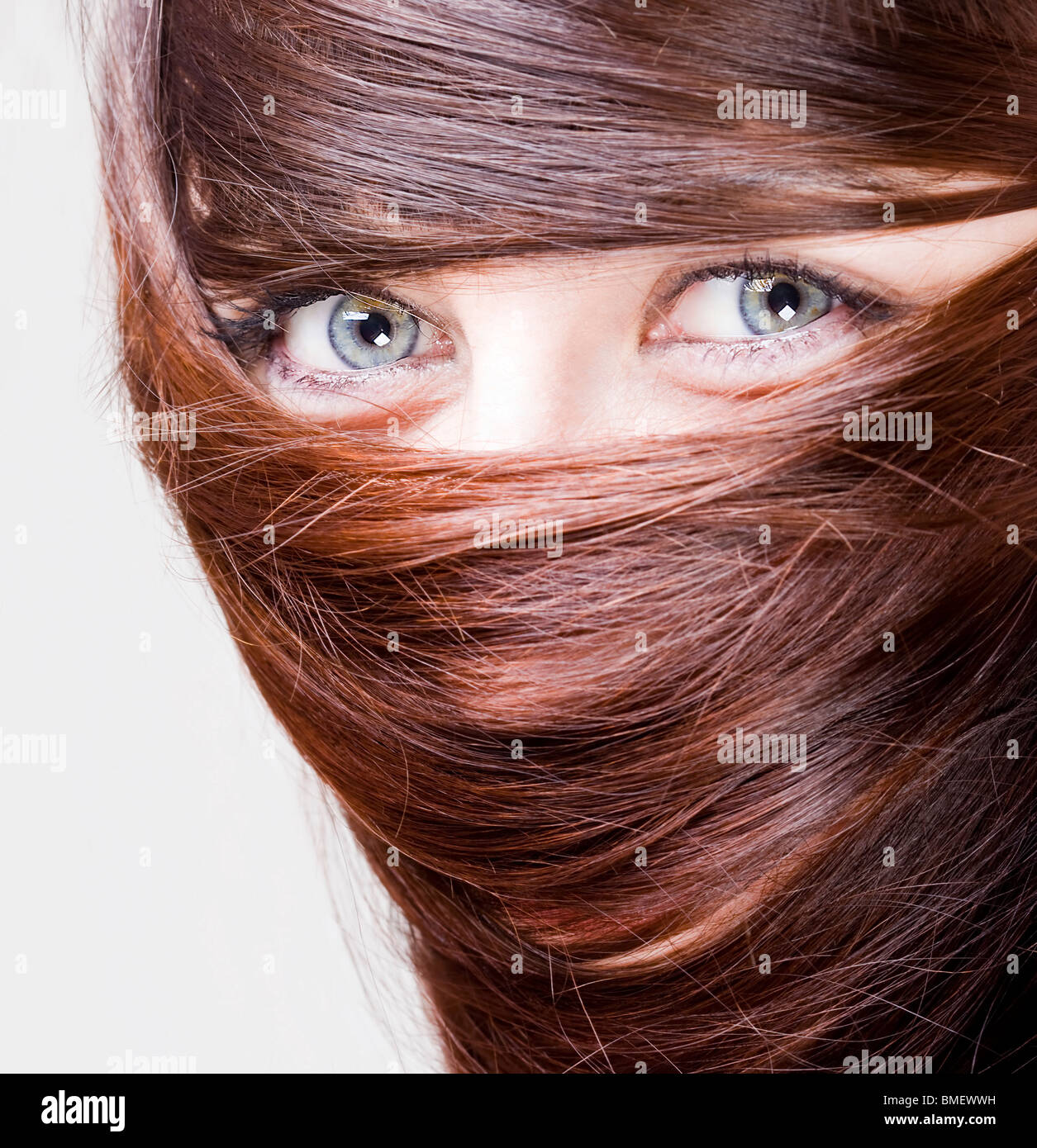 Extrange aspetto di una giovane donna con gli occhi blu con i capelli intorno agli occhi Foto Stock