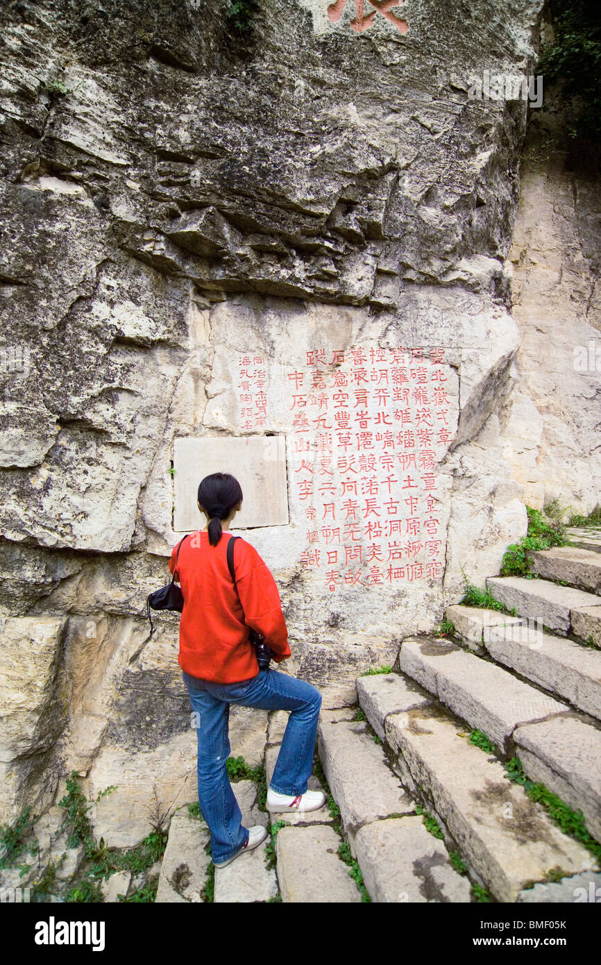 Donna cinese la lettura di poesie scolpire sulla scogliera, Heng Shan, Datong, nella provincia di Shanxi, Cina Foto Stock