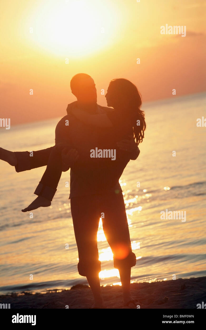 Un uomo con una donna su una spiaggia al tramonto Foto Stock