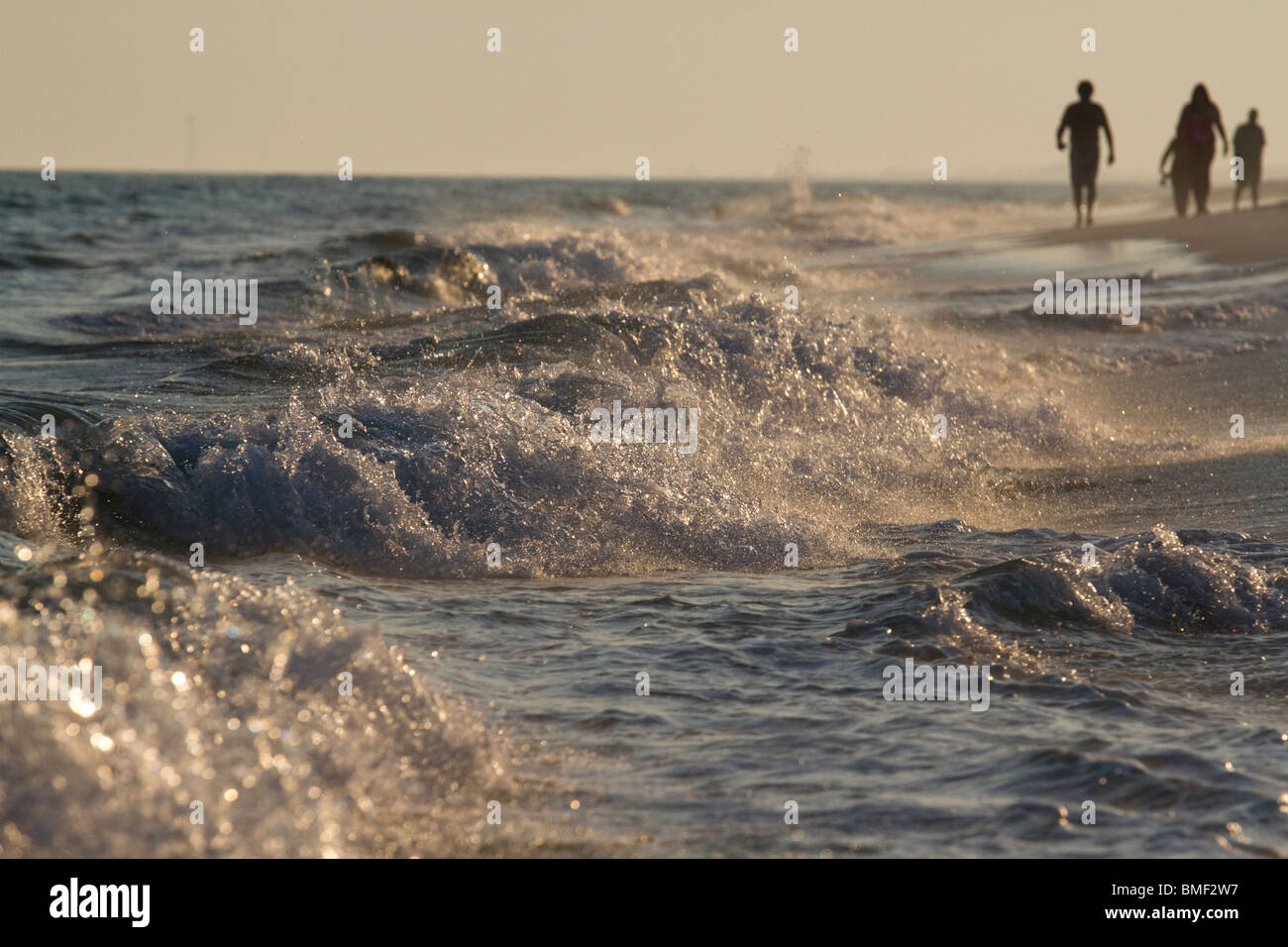 Surf, tramonto, gente che cammina su una spiaggia Foto Stock