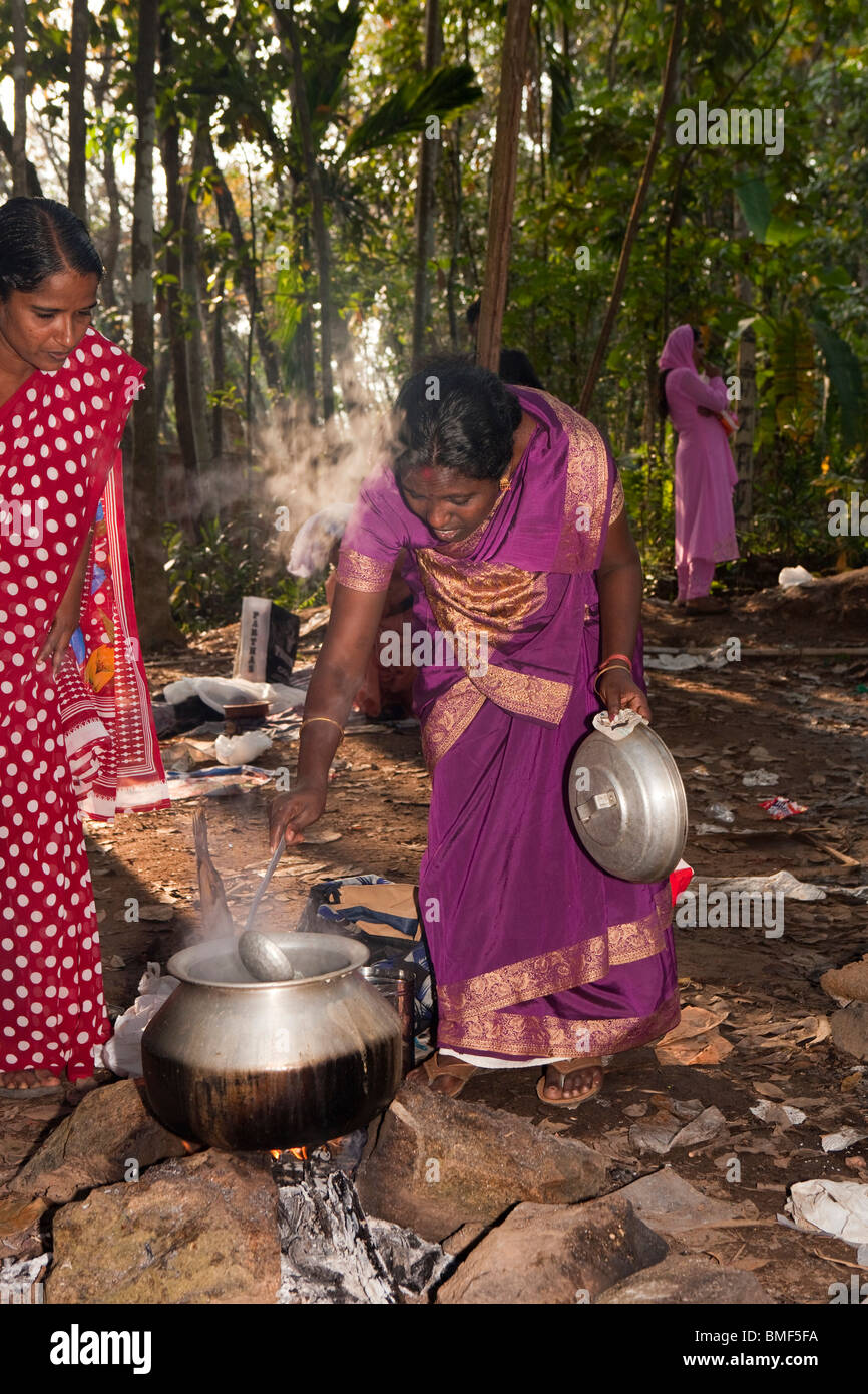 India Kerala, Kanjiramattom Kodikuthu festival, donna pongal agitazione in metallo pentola su fuoco di legno aperto Foto Stock
