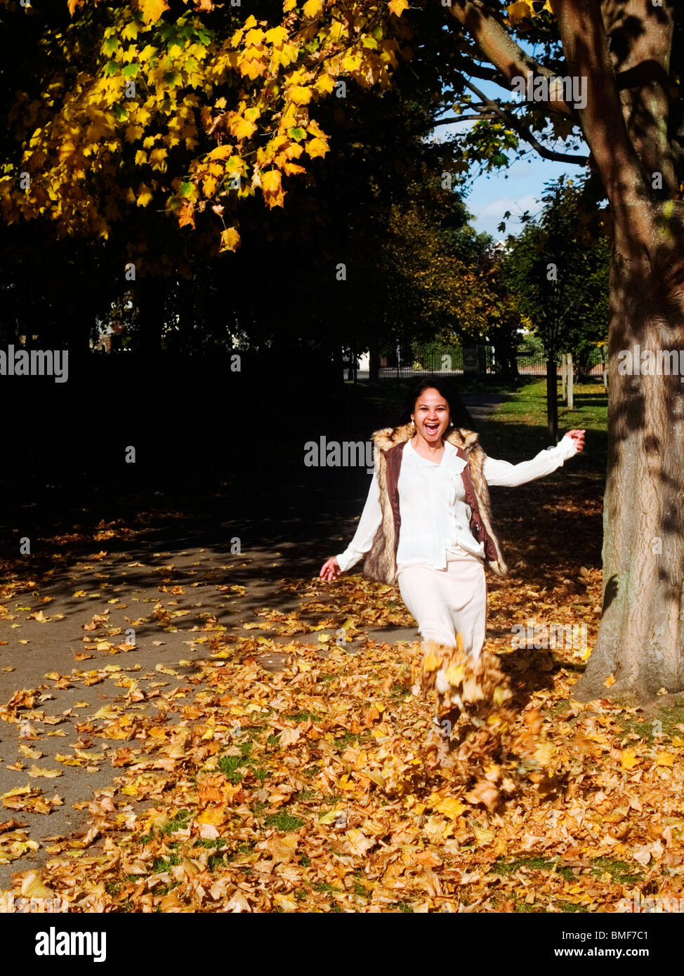 Giovane donna che si gode in un tappeto di caduto foglie di autunno Foto Stock