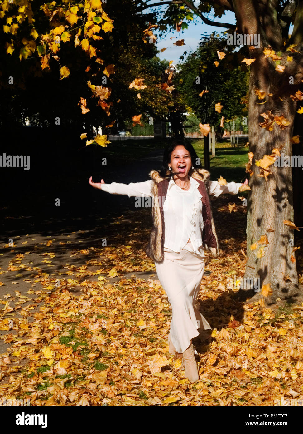 Giovane donna che si gode in un tappeto di caduto foglie di autunno Foto Stock