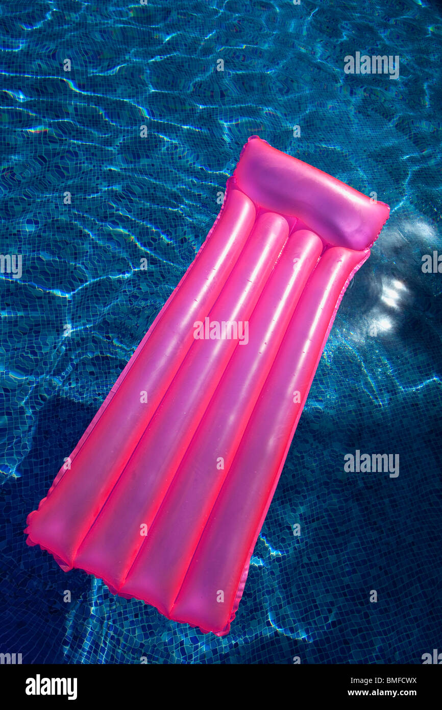 Rosa airbed lilo in piscina estiva di sole Foto Stock