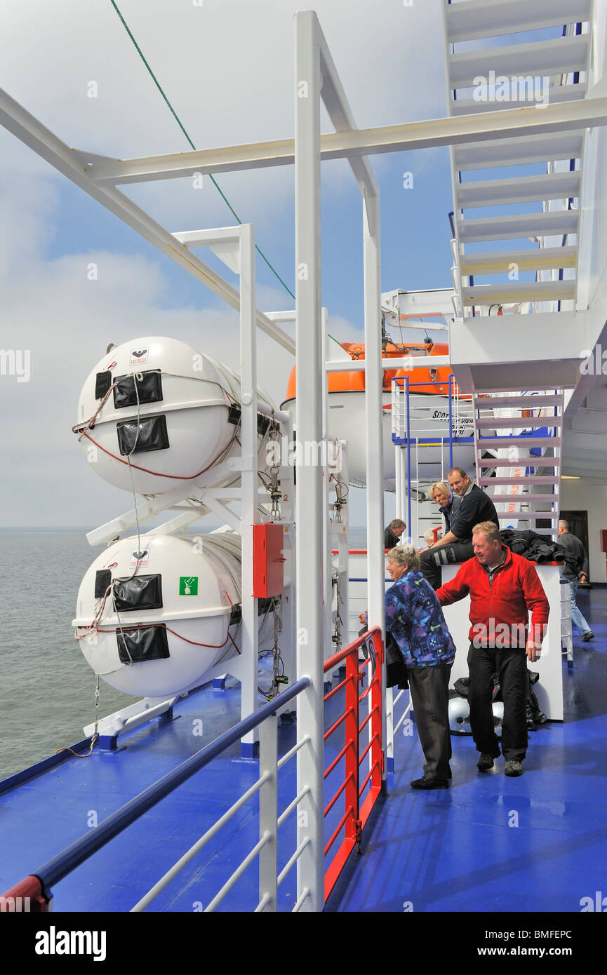 I turisti tra le zattere di salvataggio gonfiabile in hard-barattoli sgusciate e la scialuppa di salvataggio a bordo della nave traghetto, Europa Foto Stock