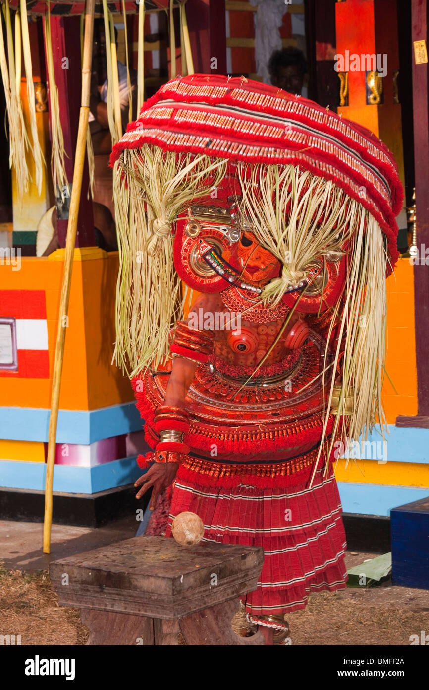 India Kerala, Cannanore (Kannur), Theyyam, divinità serpente Naga Kanni ritualmente rompendo il cocco su sgabello sacro Foto Stock