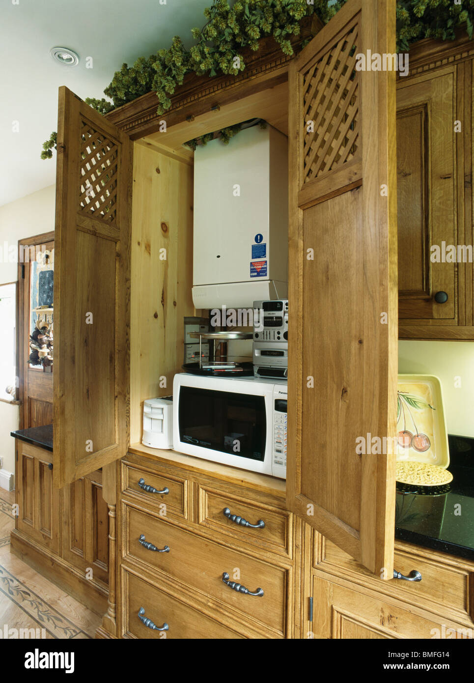 Porte aperte alla cucina con riscaldamento centrale caldaia sopra il forno a microonde e piccoli hi-fi Foto Stock