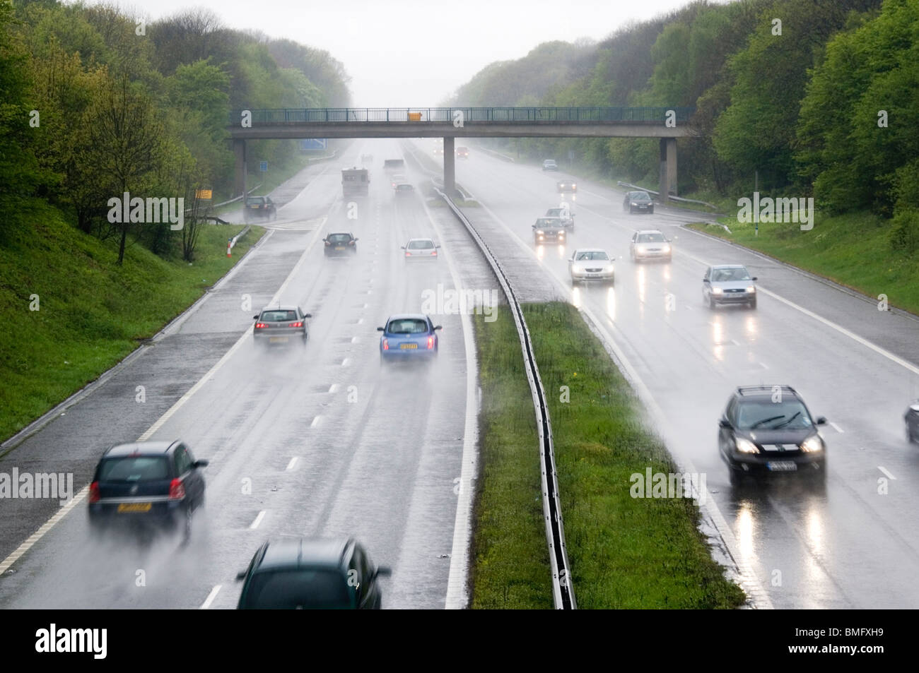 Le vetture che viaggiano a velocità in pioggia sulla autostrada M2 nel Kent, Inghilterra Foto Stock
