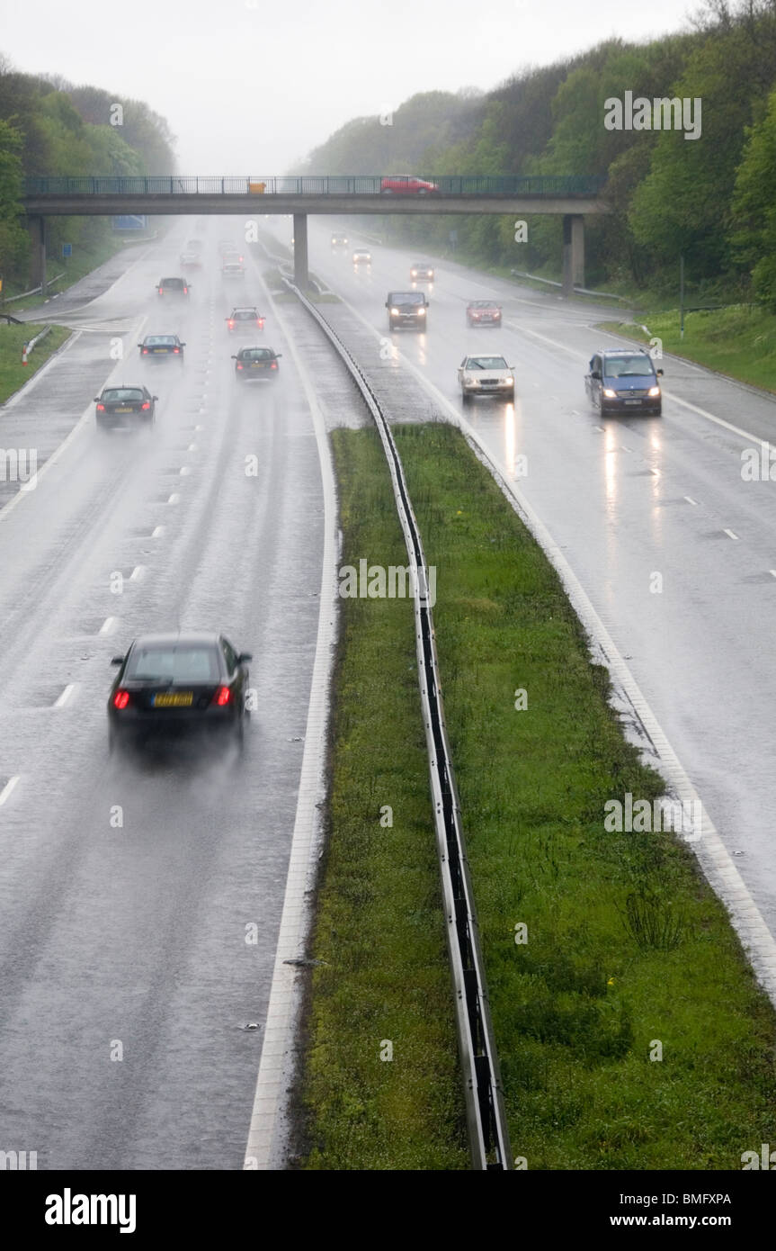 Le vetture che viaggiano a velocità sotto la pioggia sulla M2 in Kent, Inghilterra Foto Stock