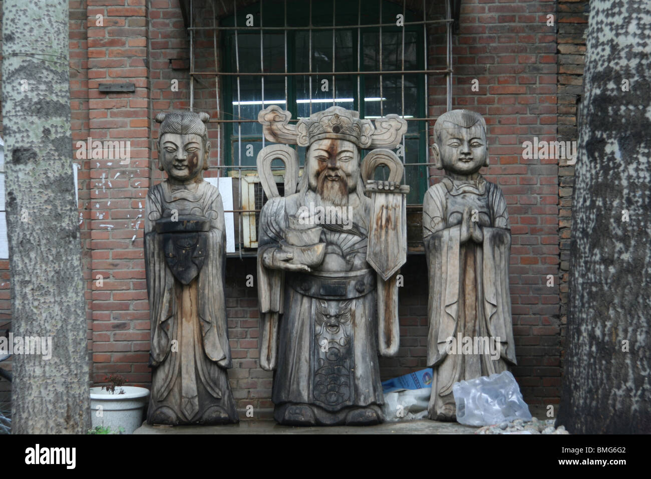 Scultura in legno di Fortune Dio e due accompagnatori, 798 Art District, Pechino, Cina Foto Stock