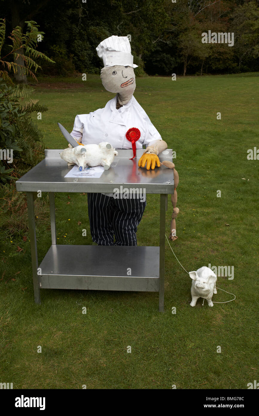 Macellaio con maiali e salsicce che producono un coltello al Bisterne Annual Scarecrow Festival, bisterne, New Forest National Park, Hampshire, Regno Unito nel mese di settembre Foto Stock