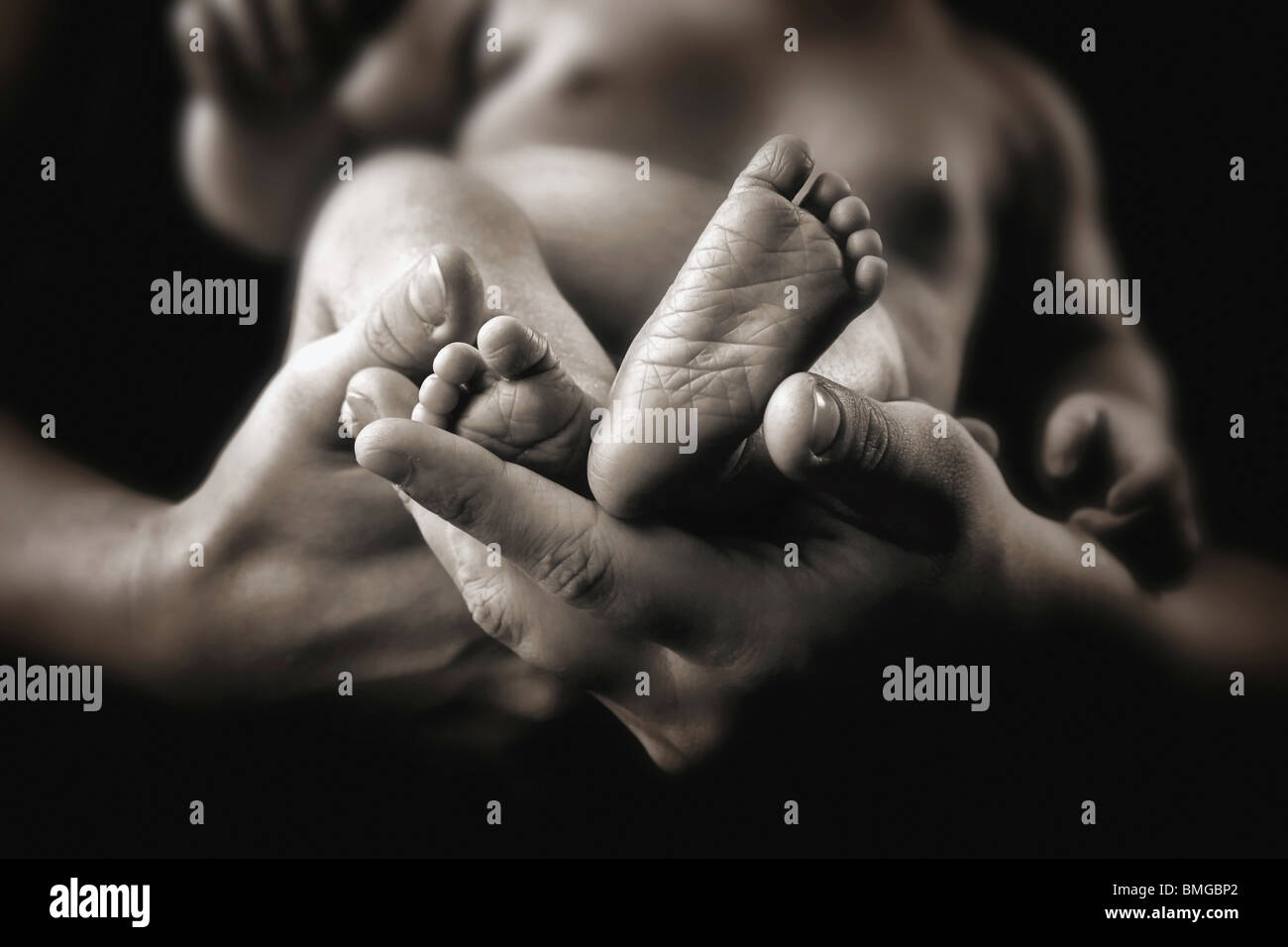 Un bambino a piedi nudi essendo tenuto da un adulto con le mani in mano Foto Stock