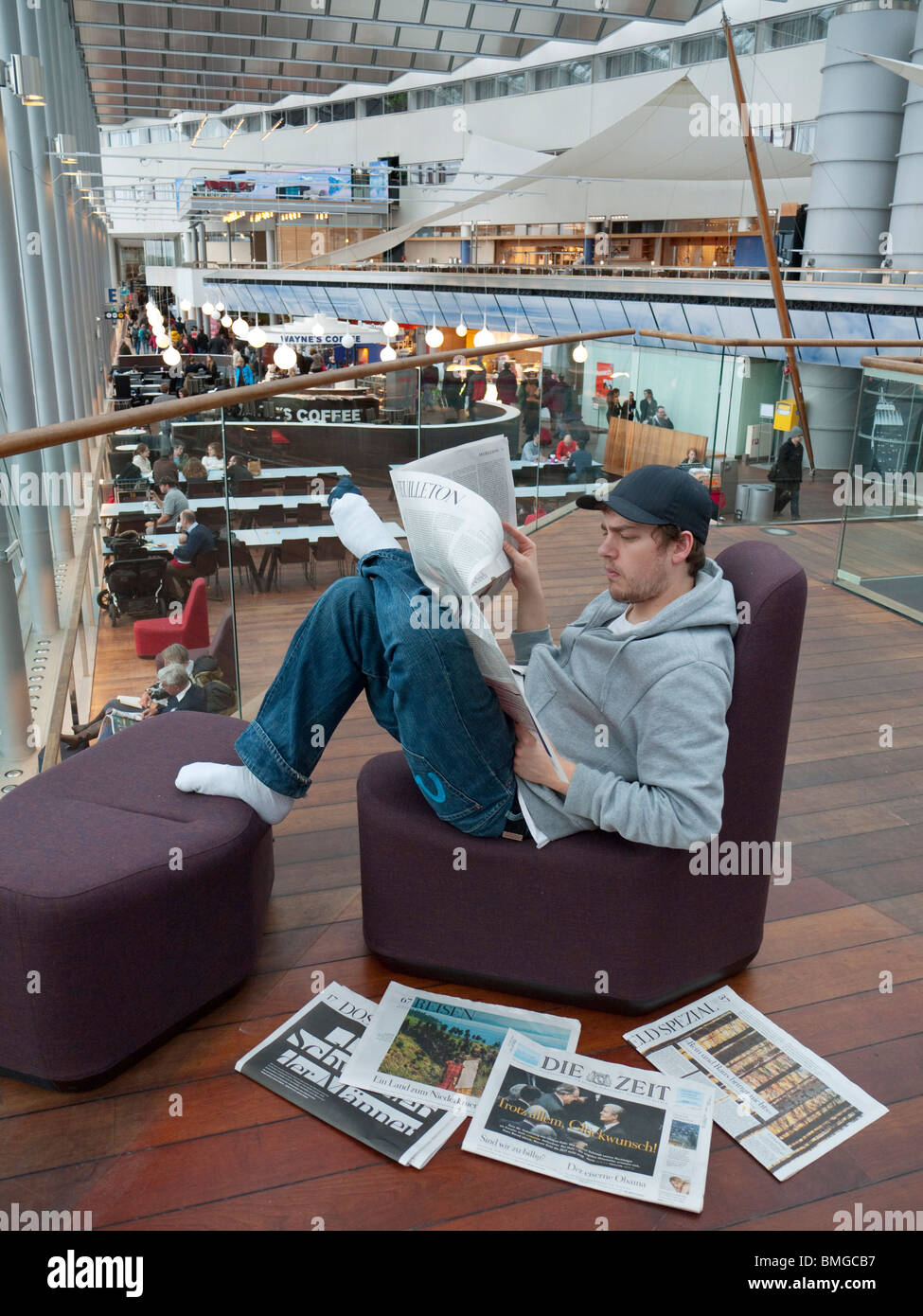 Uno studente di legge un giornale su l'aeroporto Stockholm-Arlanda. Foto Stock