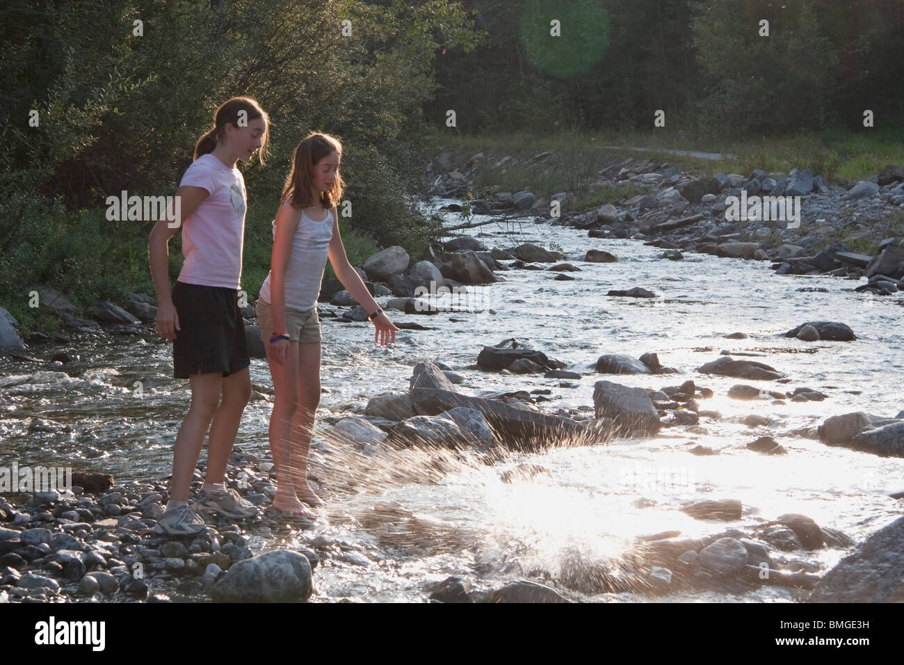 Paese di Kananaskis, Alberta, Canada; due ragazze gettando le rocce nel fiume Foto Stock