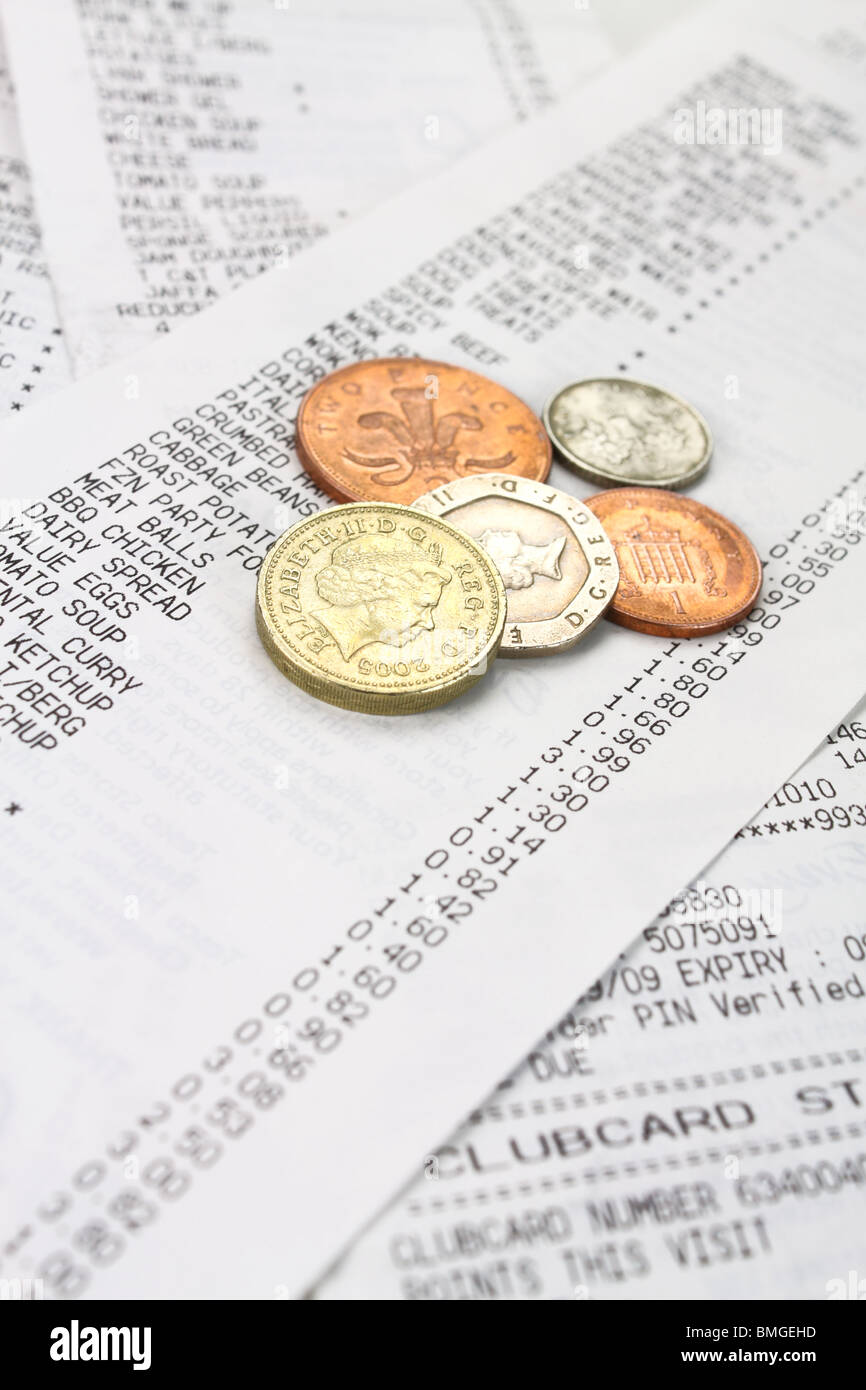 Monete sparse lungo un supermercato shopping bill Foto Stock