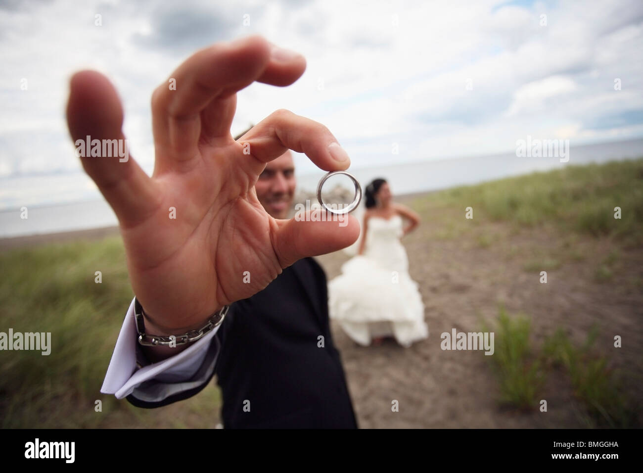 La sposa e lo sposo in piedi su una strada sterrata e lo sposo è tenendo la sua banda di nozze Foto Stock