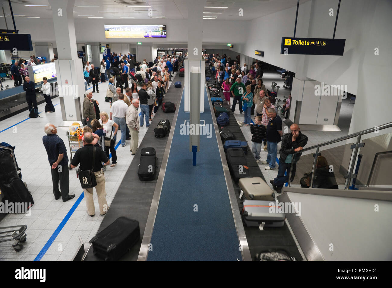 Coda di passeggeri per raccogliere i loro bagagli all'Aeroporto di Manchester UK giostra Foto Stock