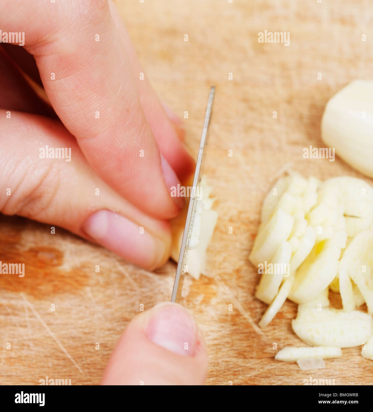 Donna tritare l'aglio con il coltello. Foto Stock