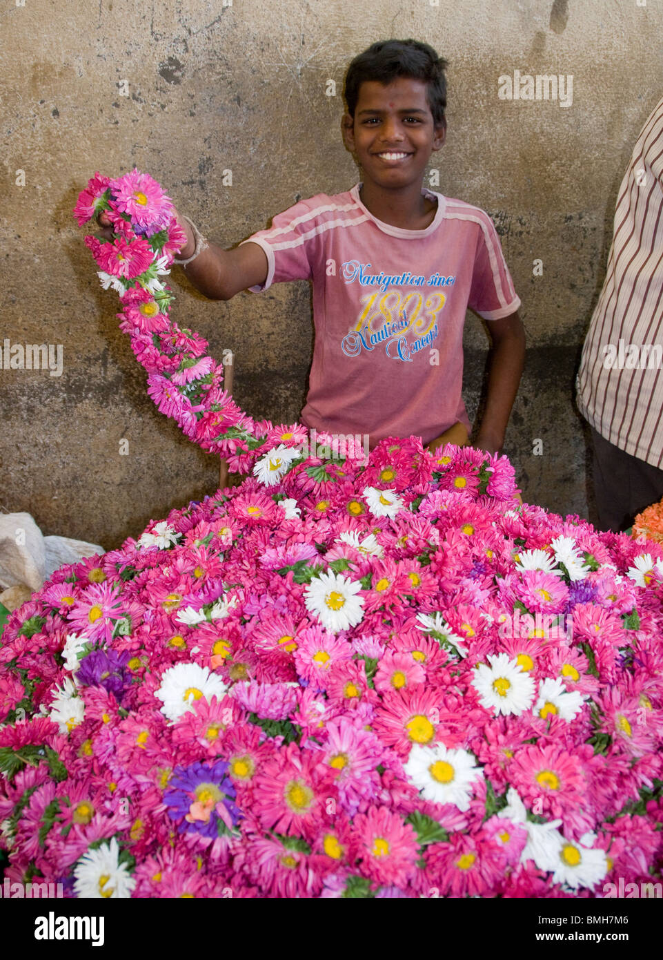 Un ragazzo la vendita di crisantemo ghirlande al mercato Devaraja di Mysore India Foto Stock